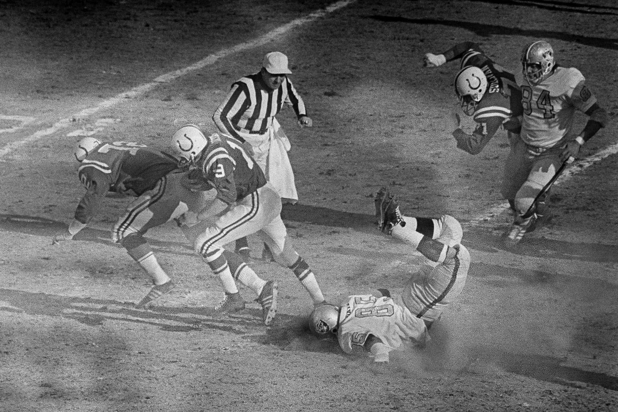 FILE - Baltimore Colts quarterback Johnny Unitas follows the blocking of Bob Vogel (72) as he runs for a first down to the Oakland Raiders 10-yard line during the first quarter of the AFC NFL football championship game at Memorial Stadium in Baltimore, Jan. 3, 1971. At right foreground, Raiders defender Carleton Oats slides head first on the ground. For the first time in 53 years, Baltimore is hosting the AFC championship game, bringing a different kind of spotlight to Charm City this weekend. 