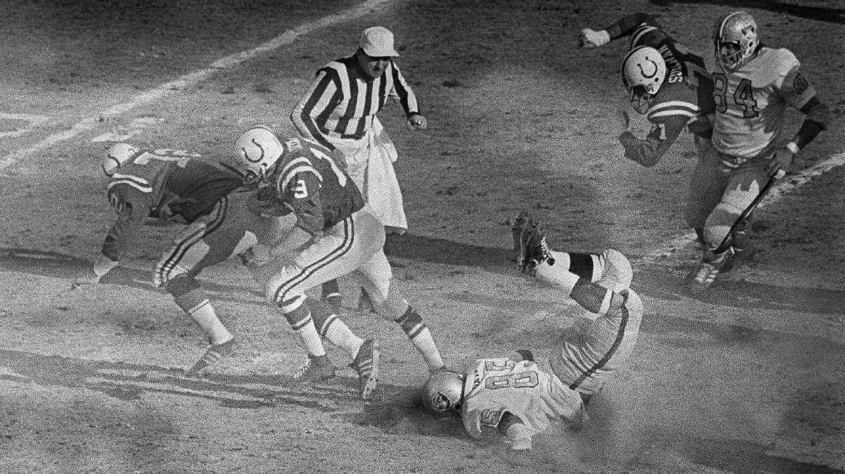 FILE - Baltimore Colts quarterback Johnny Unitas follows the blocking of Bob Vogel (72) as he runs for a first down to the Oakland Raiders 10-yard line during the first quarter of the AFC NFL football championship game at Memorial Stadium in Baltimore, Jan. 3, 1971. At right foreground, Raiders defender Carleton Oats slides head first on the ground. For the first time in 53 years, Baltimore is hosting the AFC championship game, bringing a different kind of spotlight to Charm City this weekend.