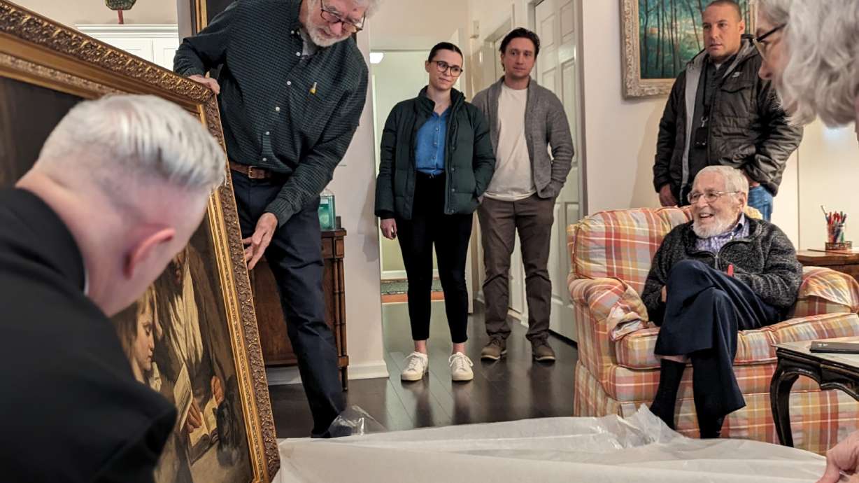 Siblings Tom Wood and Penelope Kulko assist FBI special agent Gary France in unveiling the recovered painting to Dr. Francis Wood in his Newark, New Jersey home on Jan. 11.