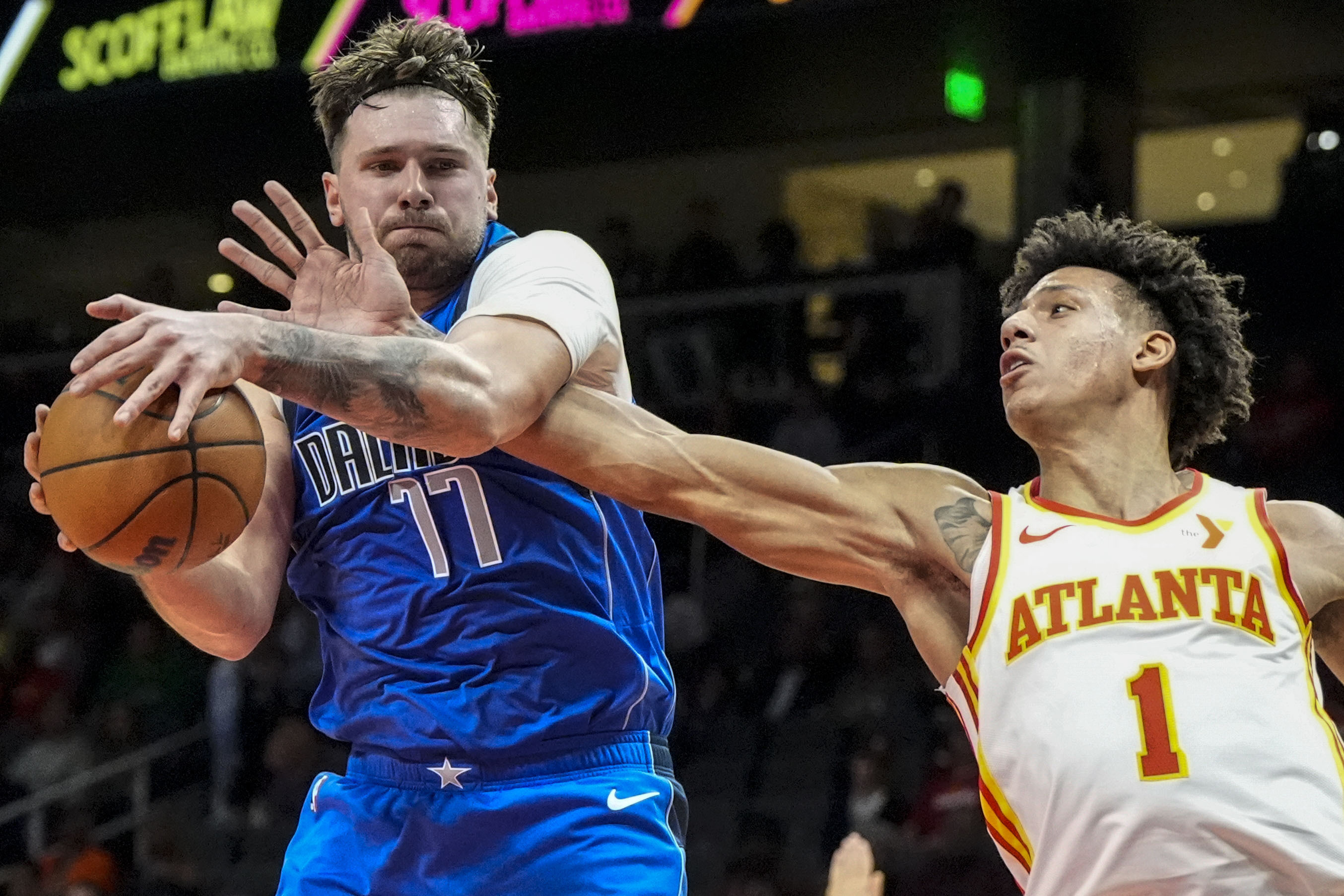 Dallas Mavericks guard Luka Doncic (77) grabs a rebopund from Atlanta Hawks forward Jalen Johnson (1) during the first half of an NBA basketball game, Friday, Jan. 26, 2024, in Atlanta. 