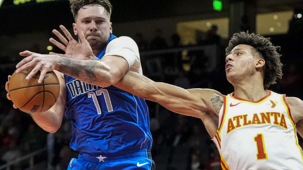 Dallas Mavericks guard Luka Doncic (77) grabs a rebopund from Atlanta Hawks forward Jalen Johnson (1) during the first half of an NBA basketball game, Friday, Jan. 26, 2024, in Atlanta.
