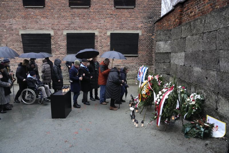 Holocaust survivors and relatives place candles next to the Death Wall in the Auschwitz Nazi death camp in Oswiecim, Poland, Saturday. Survivors of Nazi death camps marked the 79th anniversary of the liberation of the Auschwitz-Birkenau camp during World War II in a modest ceremony in southern Poland.