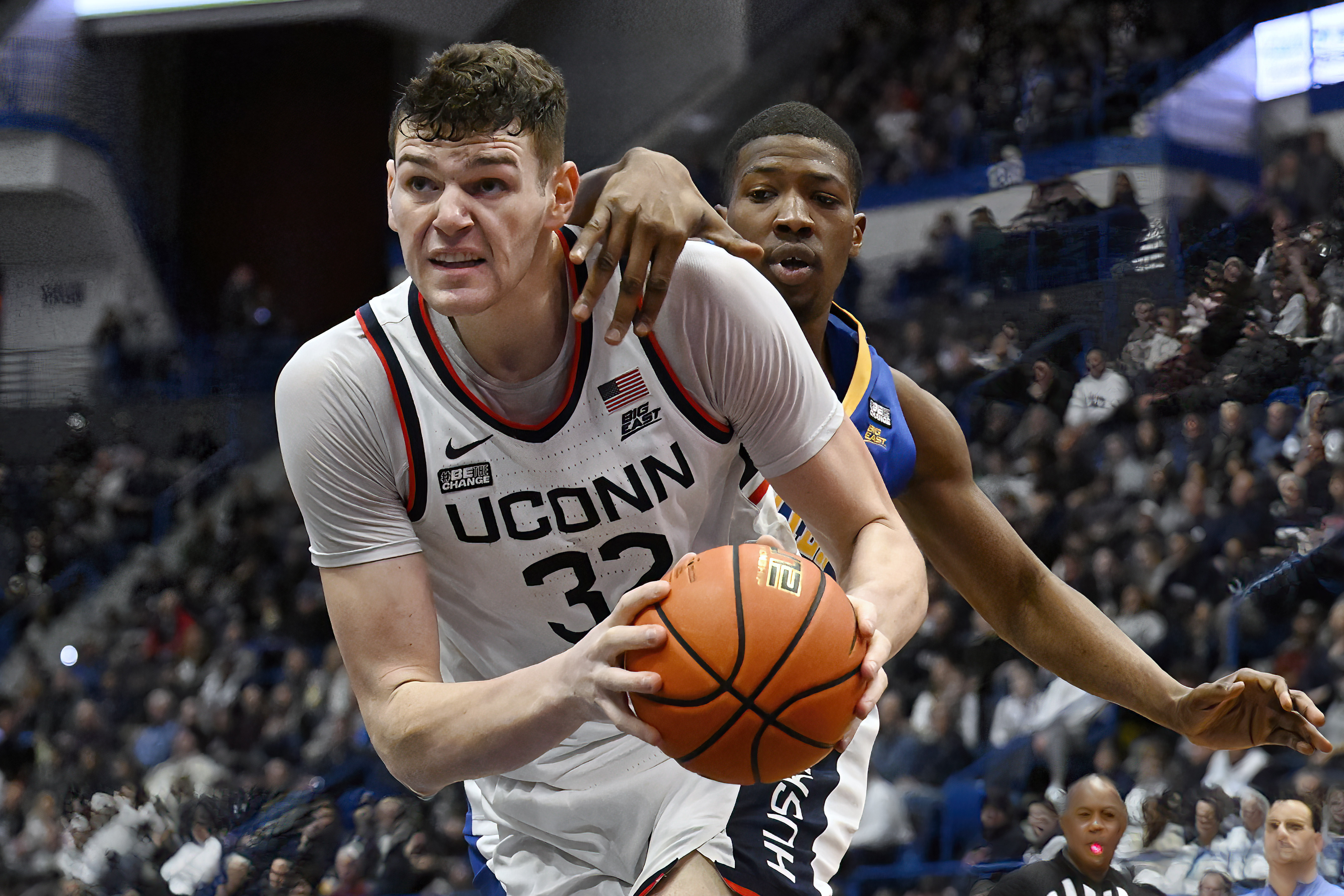 UConn center Donovan Clingan (32) drives to the basket as Xavier forward Abou Ousmane defends in the first half of an NCAA college basketball game, Sunday, Jan. 28, 2024, in Hartford, Conn.