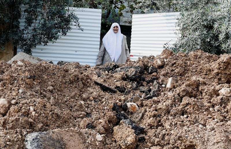 A woman reacts next to a damaged road, following an Israeli raid, in Jenin camp, in the Israeli-occupied West Bank on Monday.