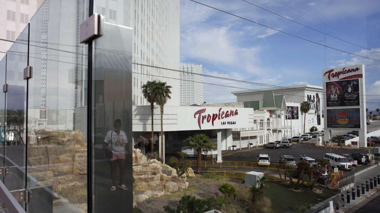 A person, reflected in glass, walks near the Tropicana Las Vegas, May 16, 2023, in Las Vegas. The building is slated to shut its doors in April 2024 to make room for a $1.5 billion Major League Baseball stadium, Bally's Corp. announced Monday.