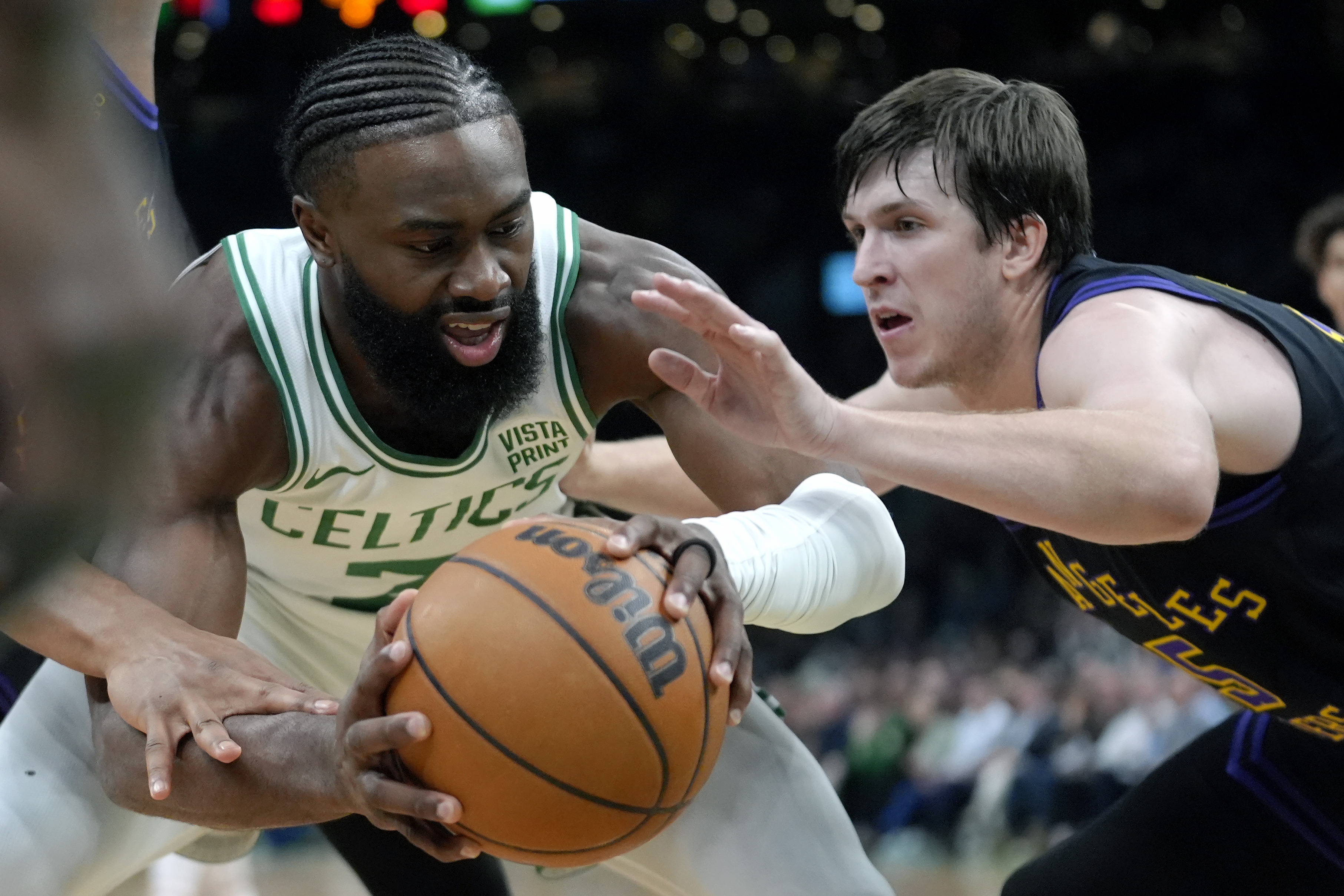 Boston Celtics guard Jaylen Brown, left, looks for an opening around Los Angeles Lakers guard Austin Reaves in the first half of an NBA basketball game, Thursday, Feb. 1, 2024, in Boston.