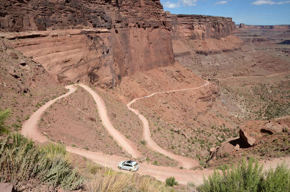 A car moves by the steep grade and switchbacks of Shafer Trail in Canyonlands National Park on Sept. 17, 2023.