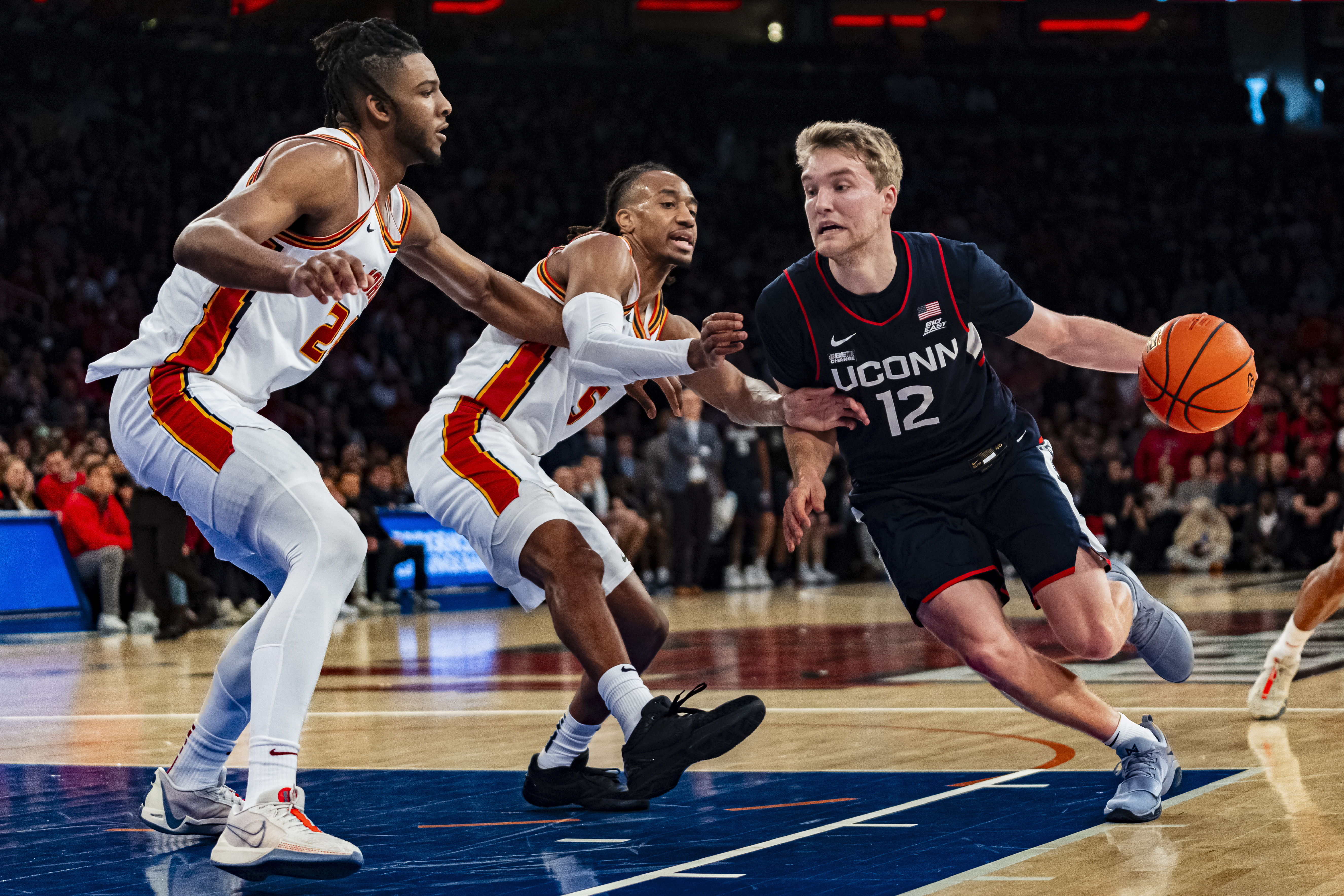 UConn guard Cam Spencer (12) drives to the basket against St. John's forward Sadiku Ibine Ayo (2) and guard Daniss Jenkins (5) during the first half of an NCAA college basketball game on Saturday, Feb. 3, 2024, in New York. 