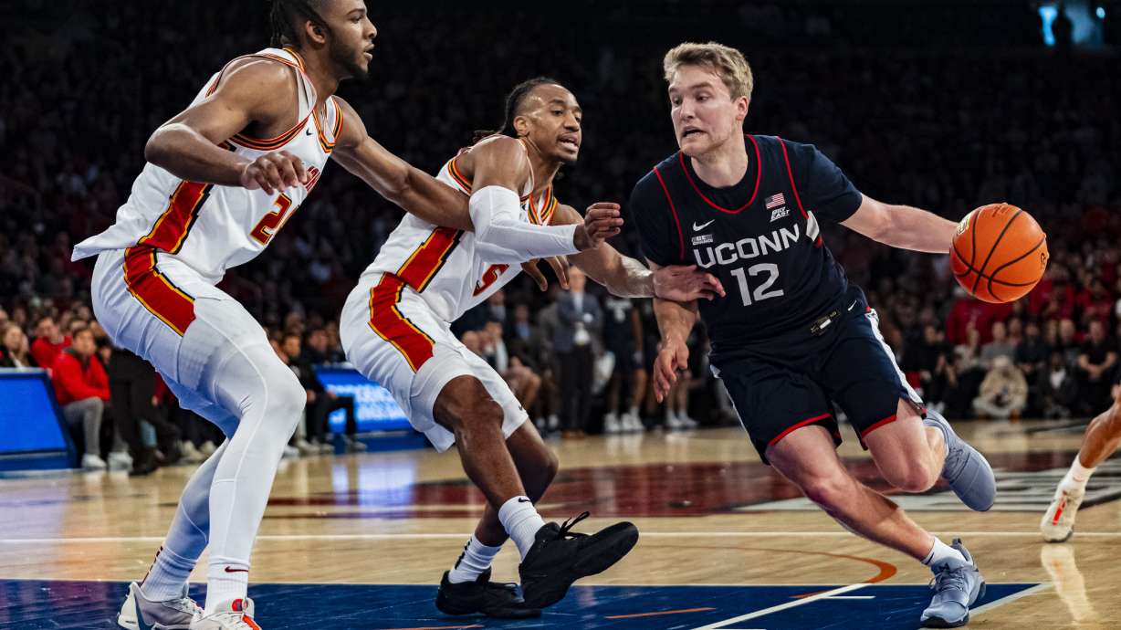 UConn guard Cam Spencer (12) drives to the basket against St. John's forward Sadiku Ibine Ayo (2) and guard Daniss Jenkins (5) during the first half of an NCAA college basketball game on Saturday, Feb. 3, 2024, in New York.