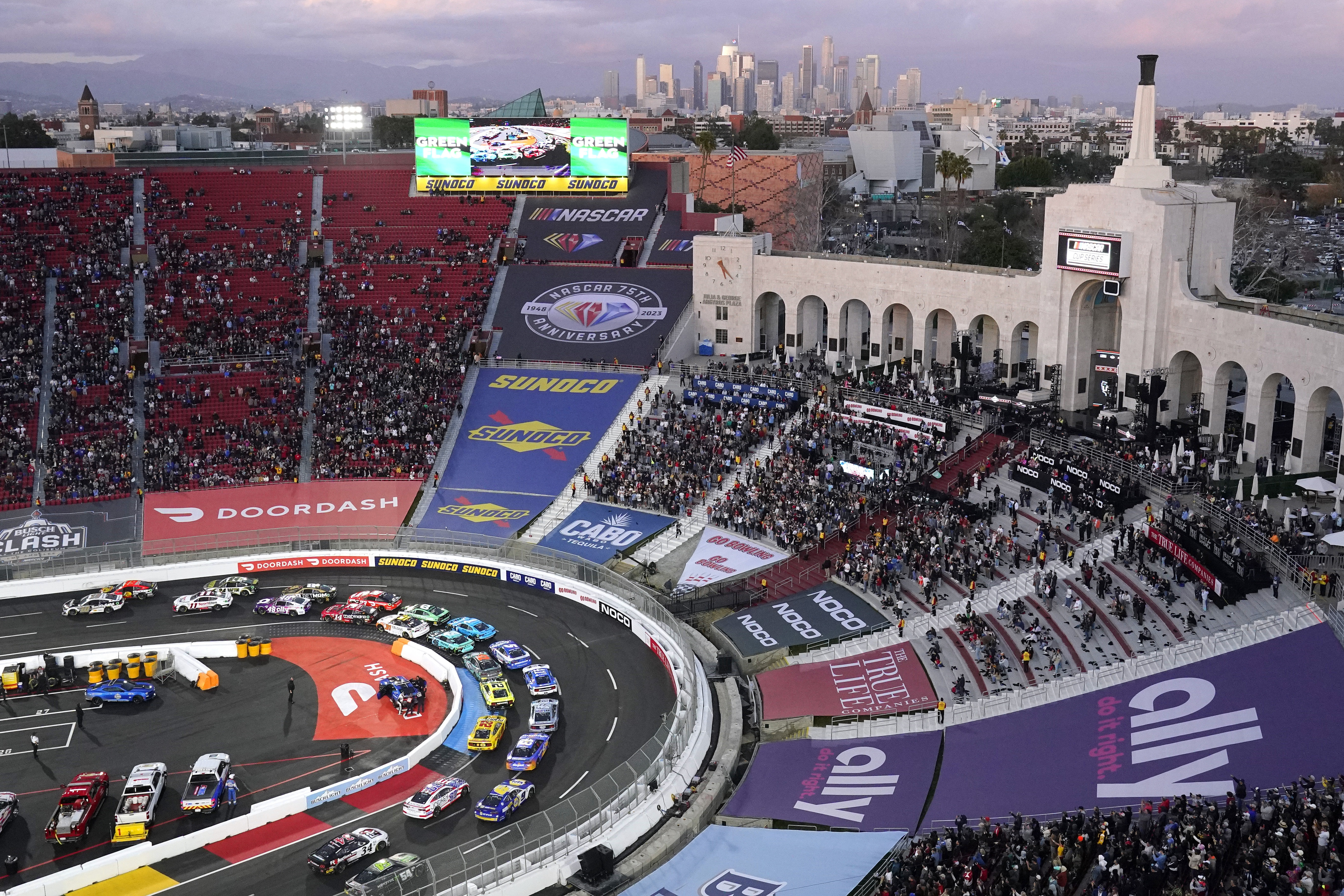 FILE - Cars race around the track as downtown Los Angeles is seen in the background during the Busch Light Clash NASCAR exhibition auto race at Los Angeles Memorial Coliseum Sunday, Feb. 5, 2023, in Los Angeles. NASCAR returns to Los Angeles Memorial Coliseum for a third consecutive year for the exhibition Clash and the immediate future of racing in Southern California is at stake.