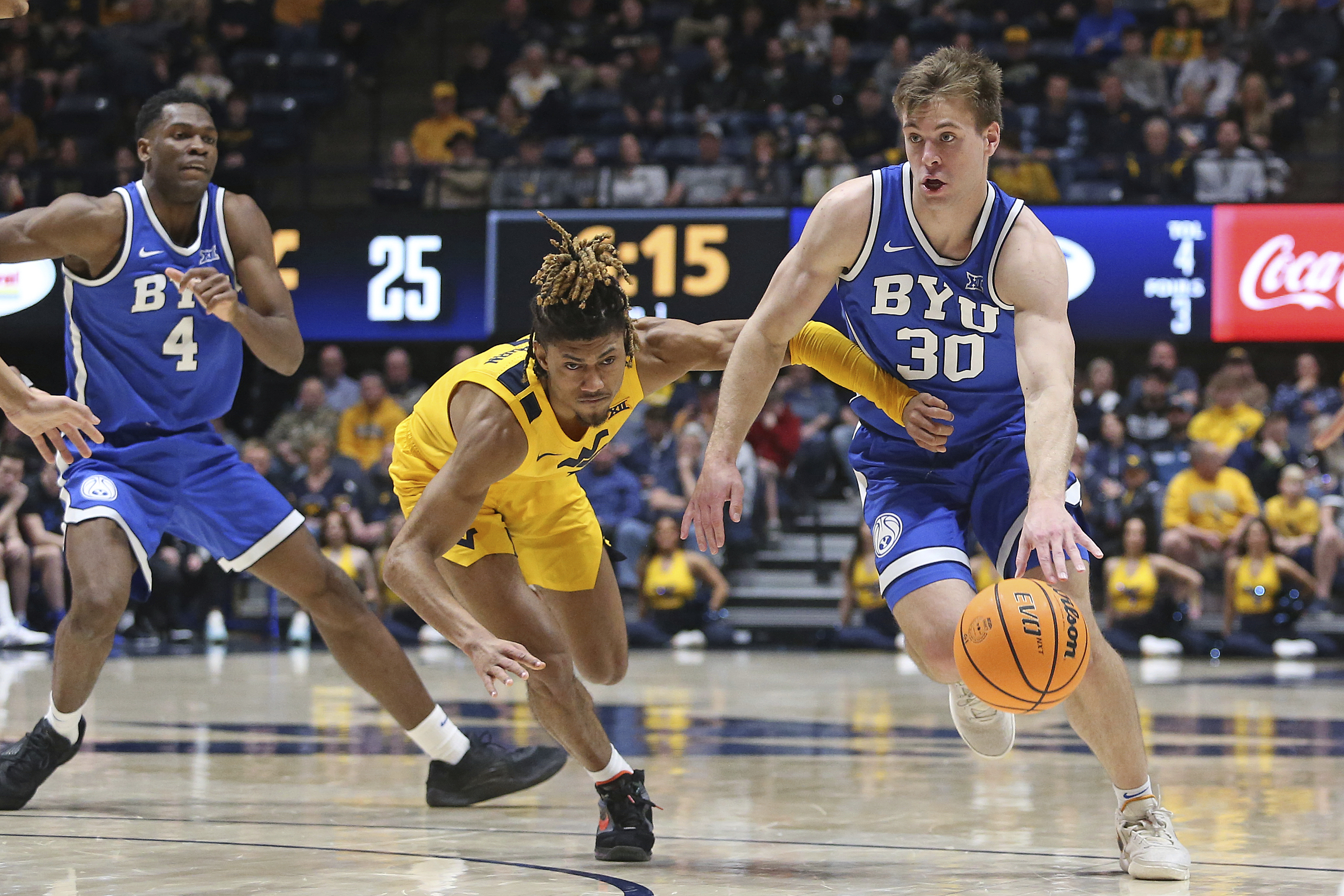 BYU guard Dallin Hall (30) is defended by West Virginia guard Noah Farrakhan, center, during the first half of an NCAA college basketball game Saturday, Feb. 3, 2024, in Morgantown, W.Va.