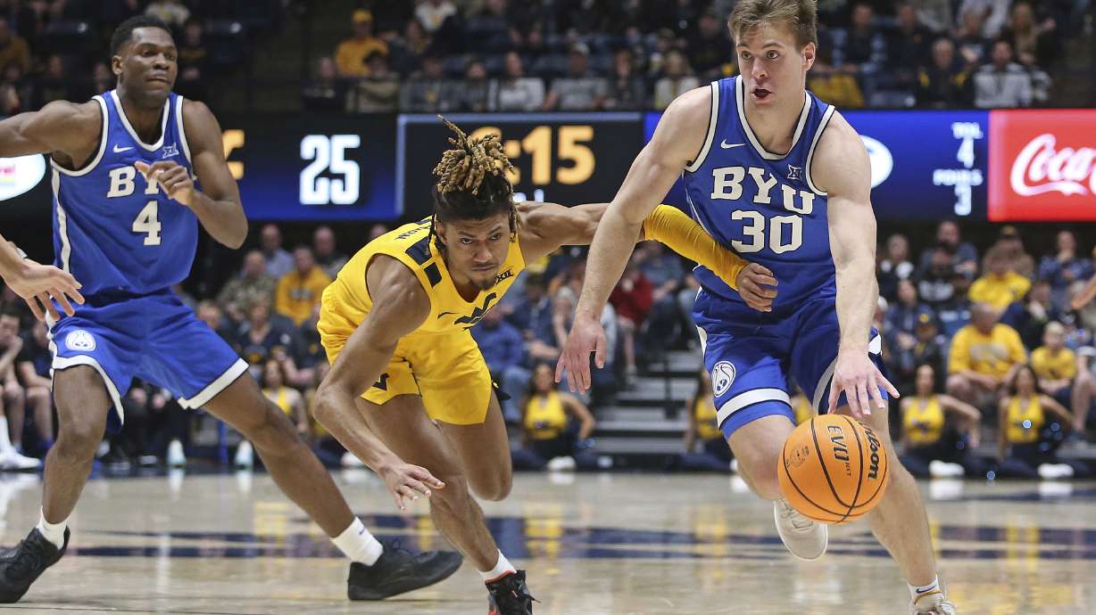 BYU guard Dallin Hall (30) is defended by West Virginia guard Noah Farrakhan, center, during the first half of an NCAA college basketball game Saturday, Feb. 3, 2024, in Morgantown, W.Va.