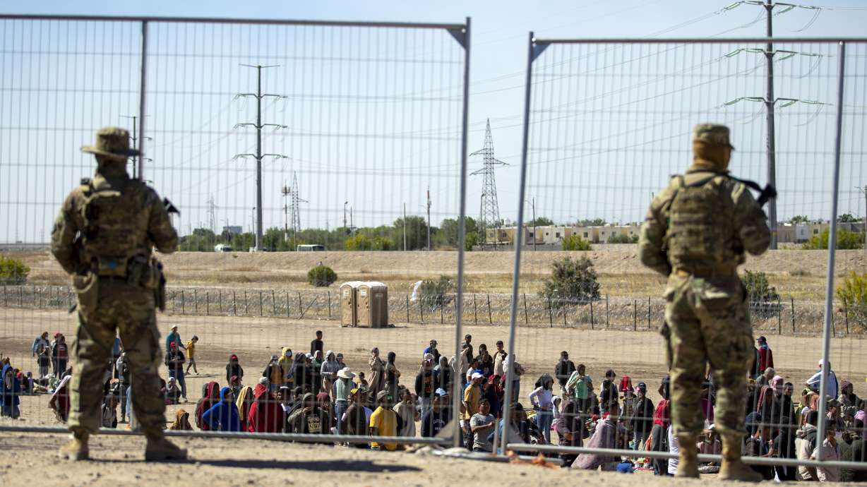 Migrants wait in line adjacent to the border fence under the watch of the Texas National Guard to enter into El Paso, Texas, May 10, 2023. Senators raced to release a highly-anticipated bill that pairs border enforcement policy with wartime aid.