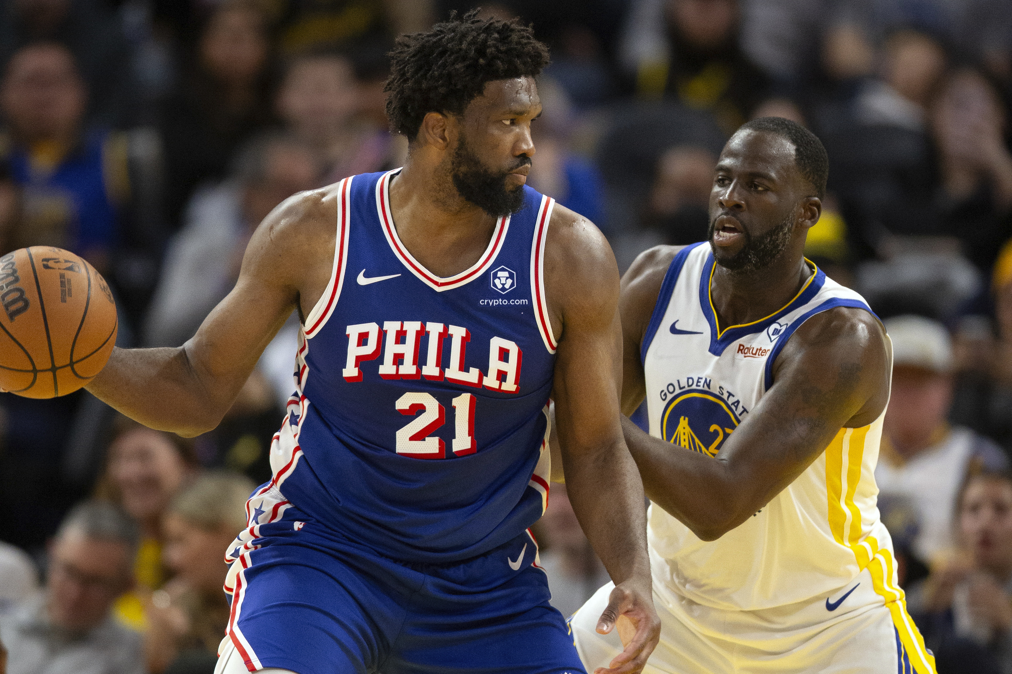 Philadelphia 76ers center Joel Embiid (21) looks to pass around Golden State Warriors forward Draymond Green (23) during the second half of an NBA basketball game, Tuesday, Jan. 30, 2024, in San Francisco.