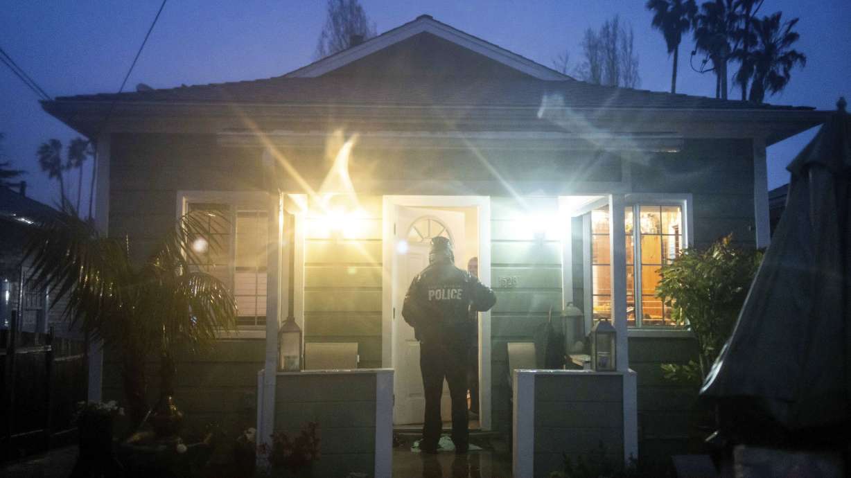 A police officer notifies a resident of rising floods during a rainstorm, Sunday, in Santa Barbara, Calif.