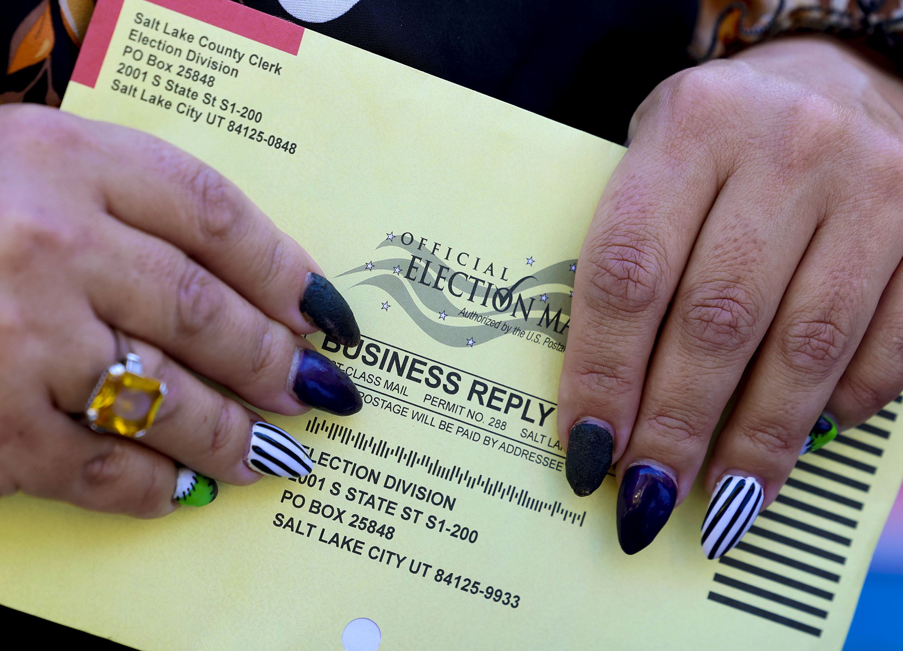 A mail-in ballot is held during a press conference at the Salt Lake City-County Building on Oct. 20, 2022. A bill introduced in the Legislature that would have required voters to ask to be sent their ballots is being overhauled by a new sponsor.