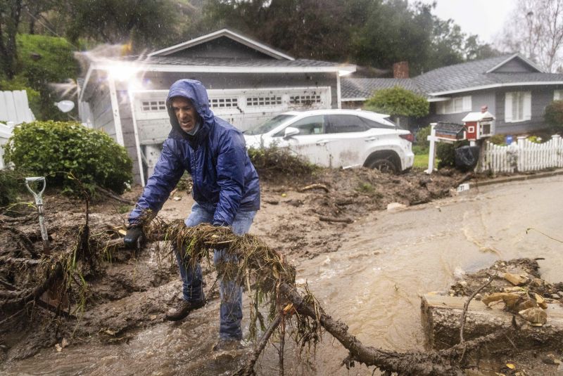 Jeffrey Raines clears debris from a mudslide at his parent's home during a rainstorm, Monday in Los Angeles. The second of back-to-back atmospheric rivers took aim at Southern California, unleashing mudslides, flooding roadways and knocking out power as the soggy state braced for another day of heavy rains.