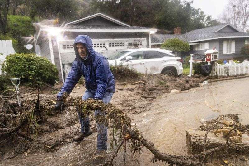 Jeffrey Raines clears debris from a mudslide at his parent's home during a rainstorm, Monday in Los Angeles. The second of back-to-back atmospheric rivers took aim at Southern California, unleashing mudslides, flooding roadways and knocking out power as the soggy state braced for another day of heavy rains.
