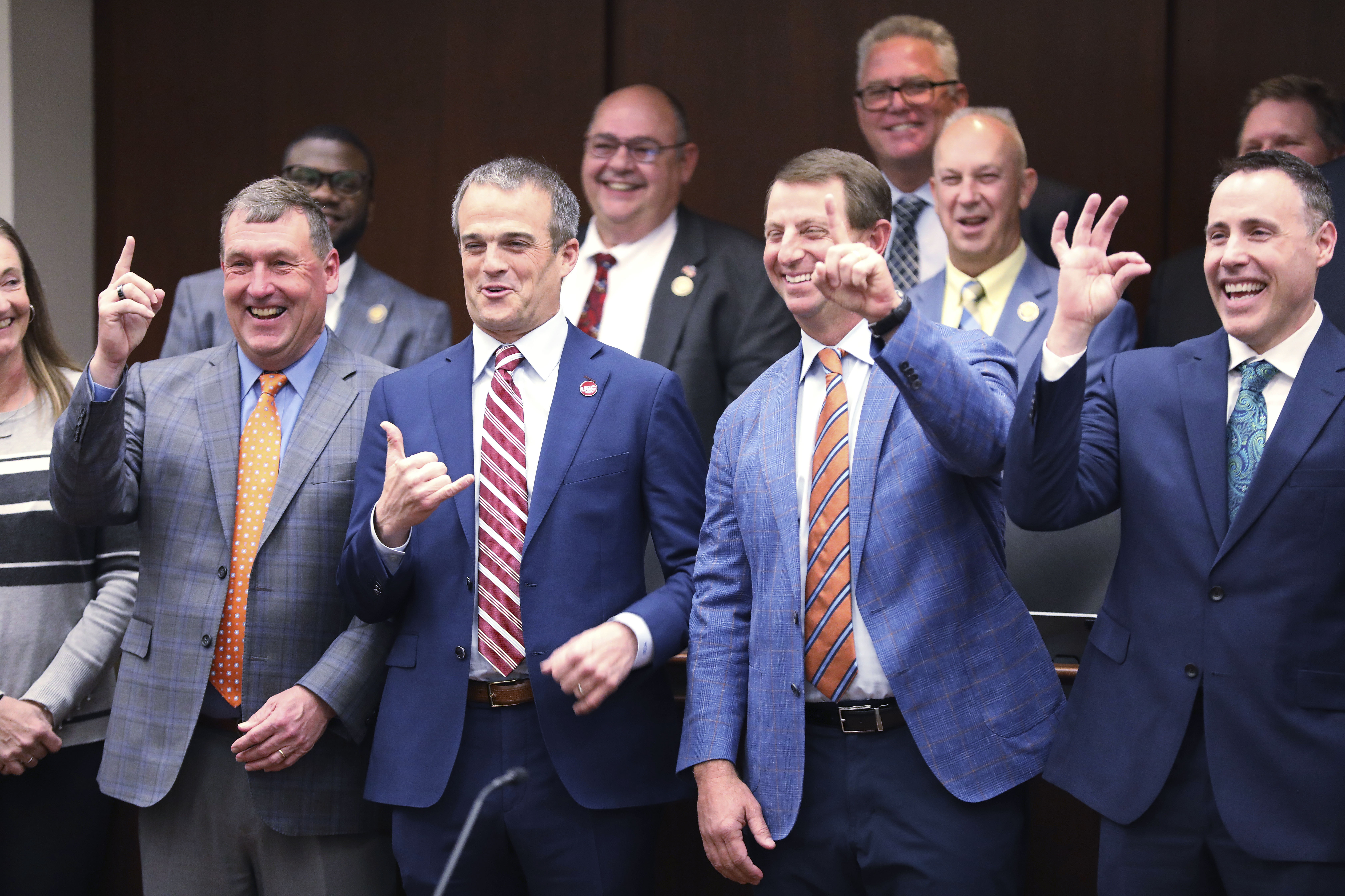 From left to right, Clemson men's soccer coach Mike Noonan, South Carolina football coach Shane Beamer, Clemson football coach Dabo Swinney and Coastal Carolina football coach Tim Beck pose for photos with lawmakers before a meeting of a South Carolina House committee considering a bill allowing schools to help athletes with name, image and likeness deals on Tuesday, Feb. 6, 2024, in Columbia, S.C. 