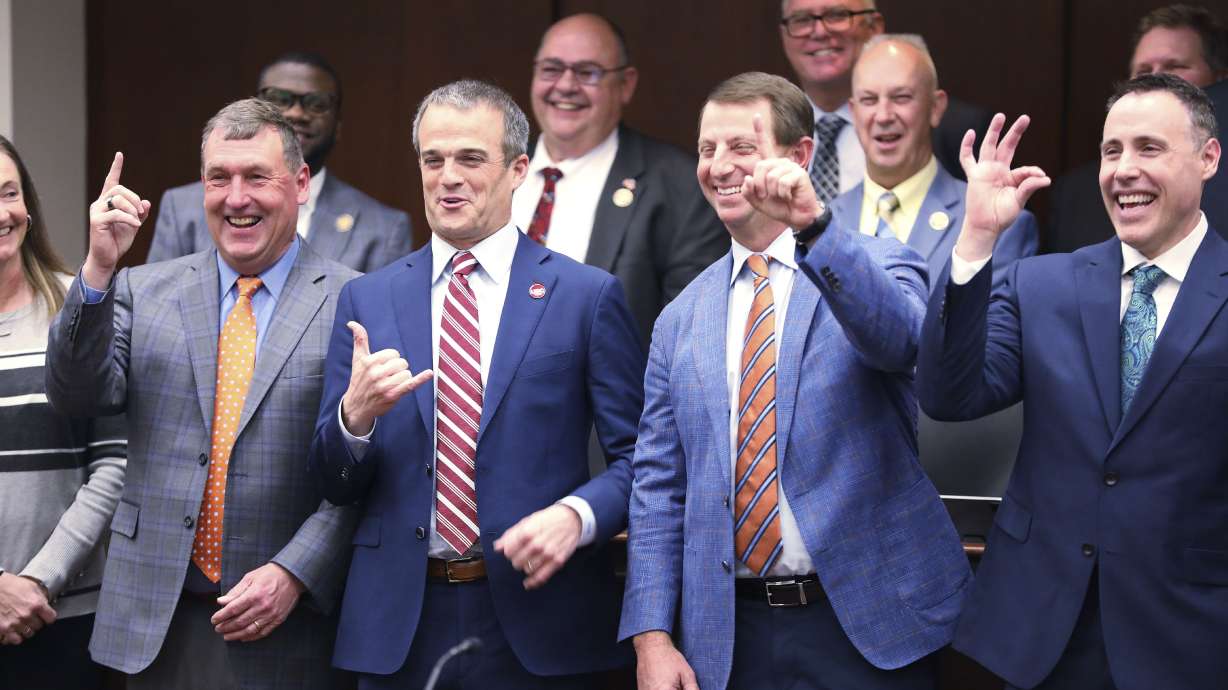 From left to right, Clemson men's soccer coach Mike Noonan, South Carolina football coach Shane Beamer, Clemson football coach Dabo Swinney and Coastal Carolina football coach Tim Beck pose for photos with lawmakers before a meeting of a South Carolina House committee considering a bill allowing schools to help athletes with name, image and likeness deals on Tuesday, Feb. 6, 2024, in Columbia, S.C.