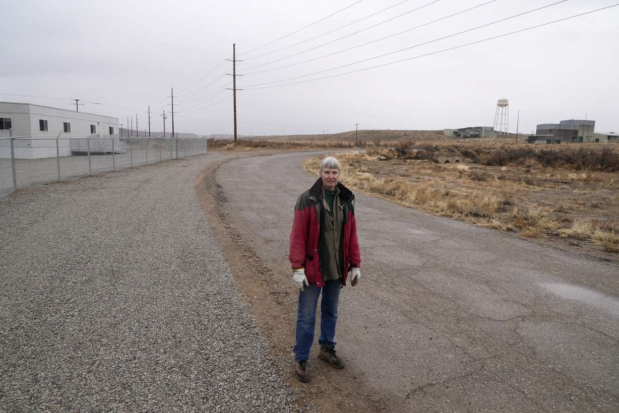 Gayna Salinas stands near a trailer, left, on land owned by Anson Resources, and a defunct uranium mine, right, Jan. 25, 2024, in Green River, Utah. The Australian company with its U.S. subsidiaries is eyeing a nearby area to extract lithium. Salinas, whose family farms in the rural community, said she was skeptical about the project's benefits.