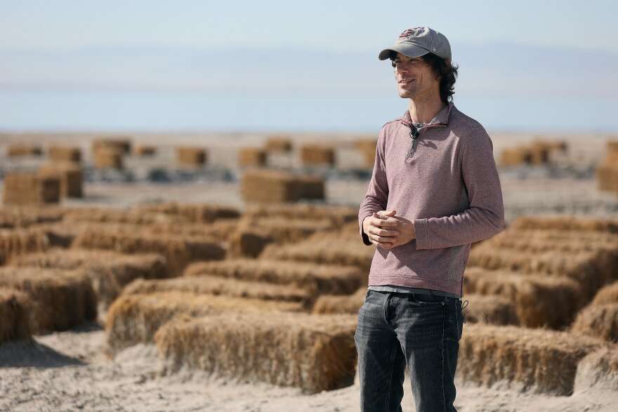 Charlie Diamond, University of California, Riverside, Earth and Planetary Sciences Department academic coordinator, talks about the Salton Sea during an interview in front of hay bales used for dust mitigation by Bombay Beach, Calif., on Tuesday, Dec. 12, 2023.