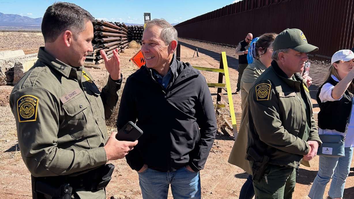 U.S. Rep. John Curtis, center speaks with a U.S. Customs and Border Protection official Thursday to the U.S.-Mexico Border near Sierra Vista, Arizona. The wall dividing the U.S. and Mexican sides is visible on the right.