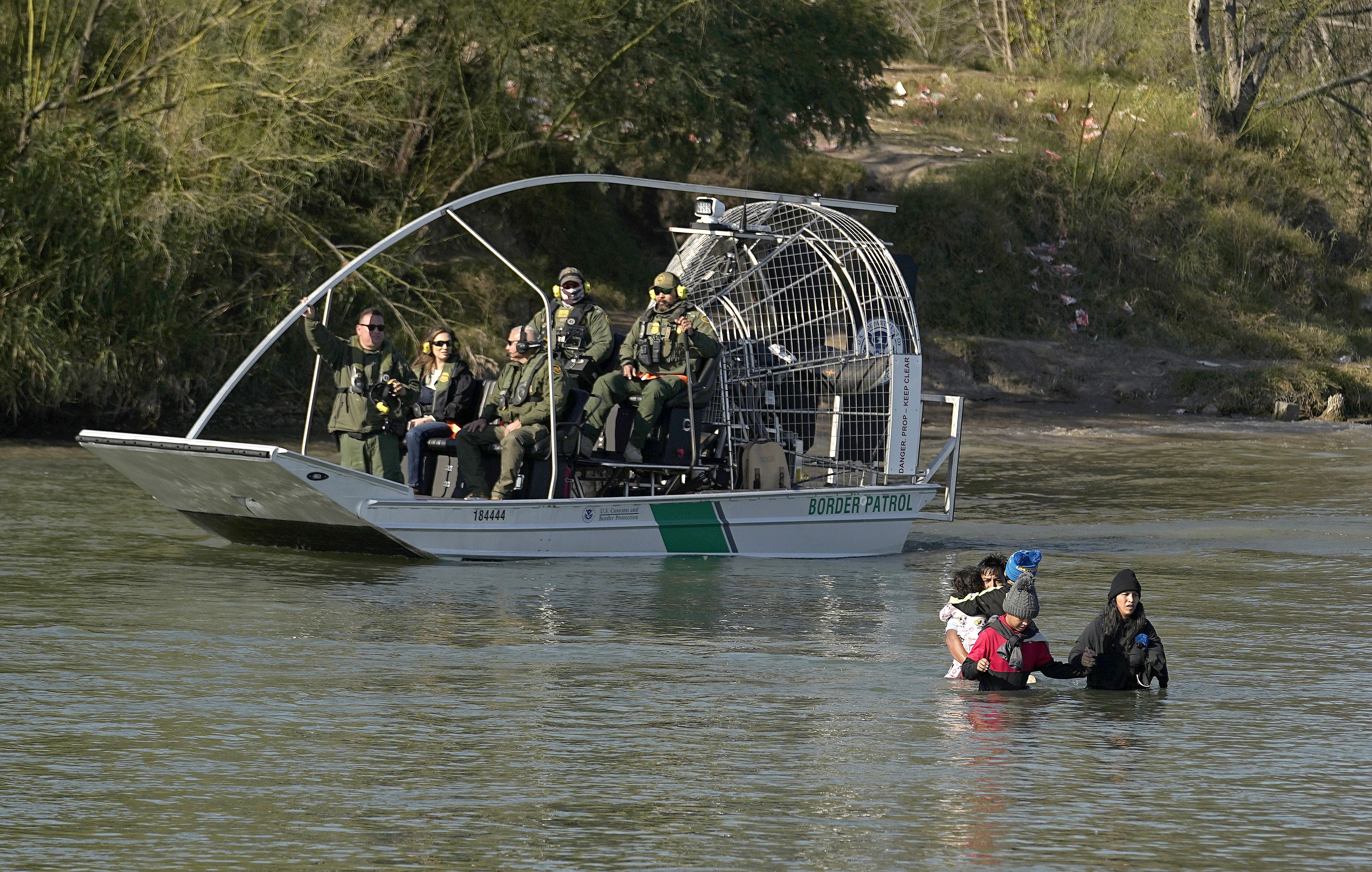 Border patrol agents watch as migrants cross the Rio Grande at the Texas-Mexico border, Jan. 3, in Eagle Pass, Texas.