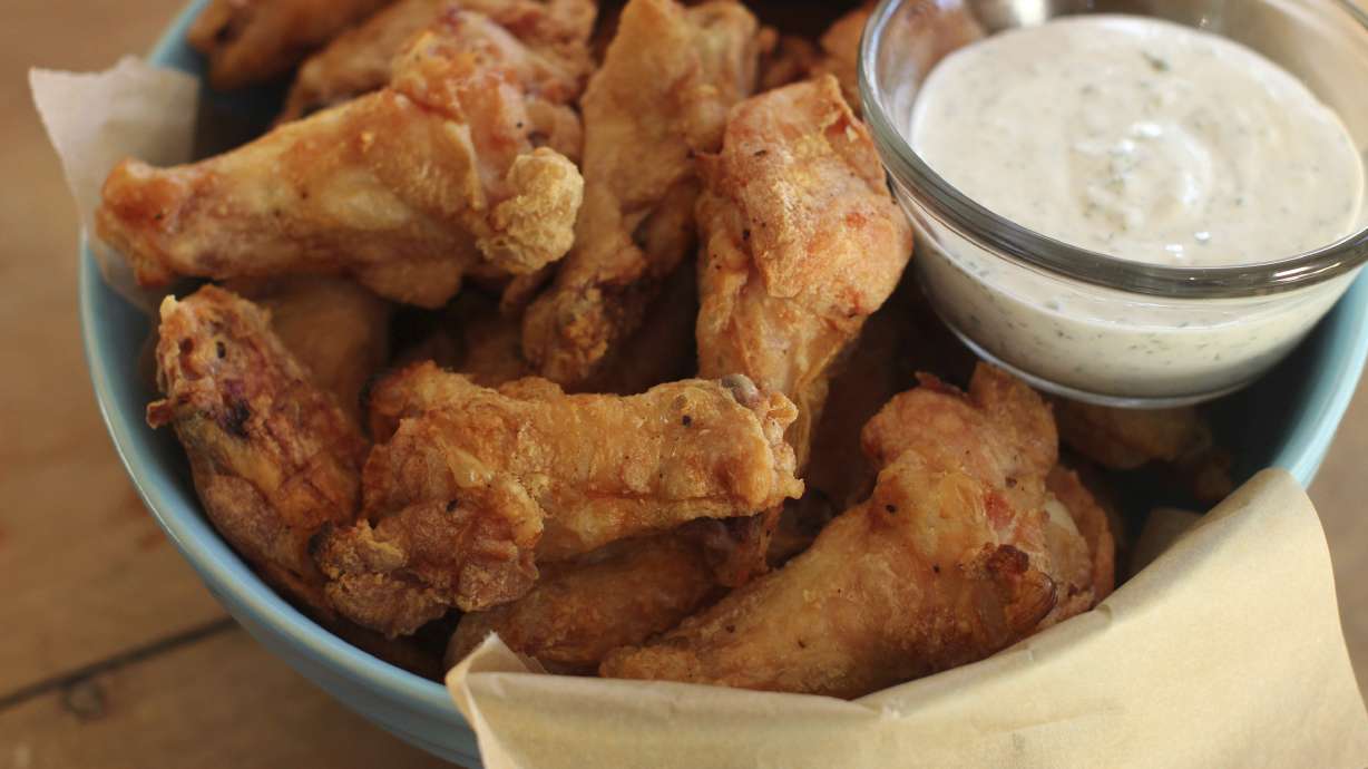 FILE - Party chicken wings with cilantro sour cream dip and honey sriracha are displayed in Concord, N.H., on Nov. 16, 2015. Preparing and keeping foods at the right temperature, avoiding cross contamination -- no double dipping! -- and being mindful about leaving out perishable snacks like chicken wings, meatballs and veggie platters are all keys to avoiding illness at your Super Bowl party, health experts said.