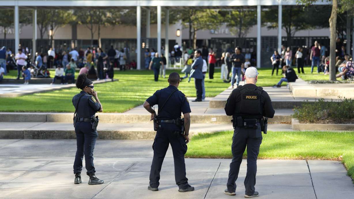 Houston police officers watch over displaced churchgoers outside Lakewood Church, Sunday in Houston, after a reported shooting during a Spanish church service.