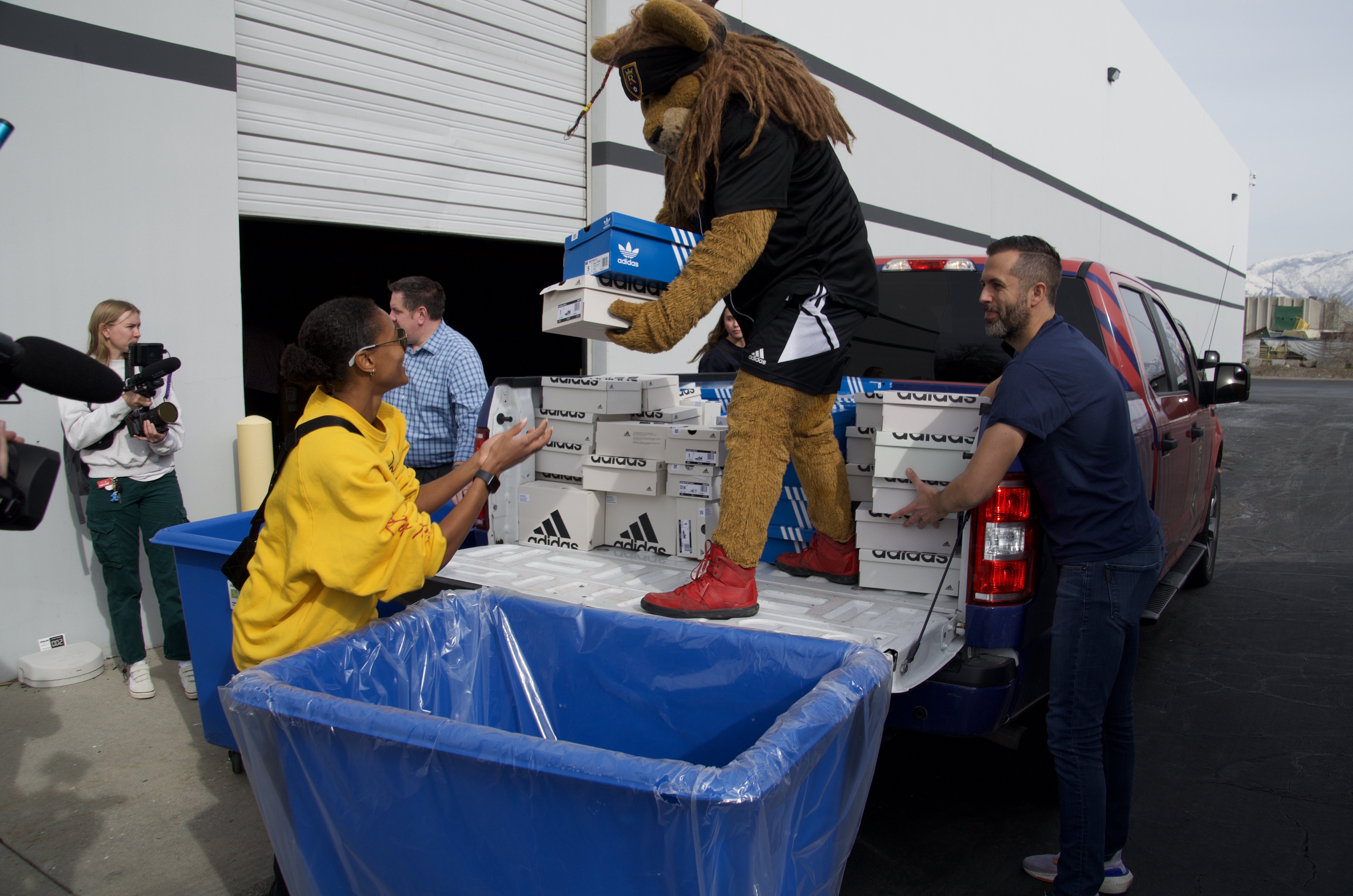 Leo the Lion and Utah Royals player Imani Dorsey help unload donated sneakers Monday in West Valley City.