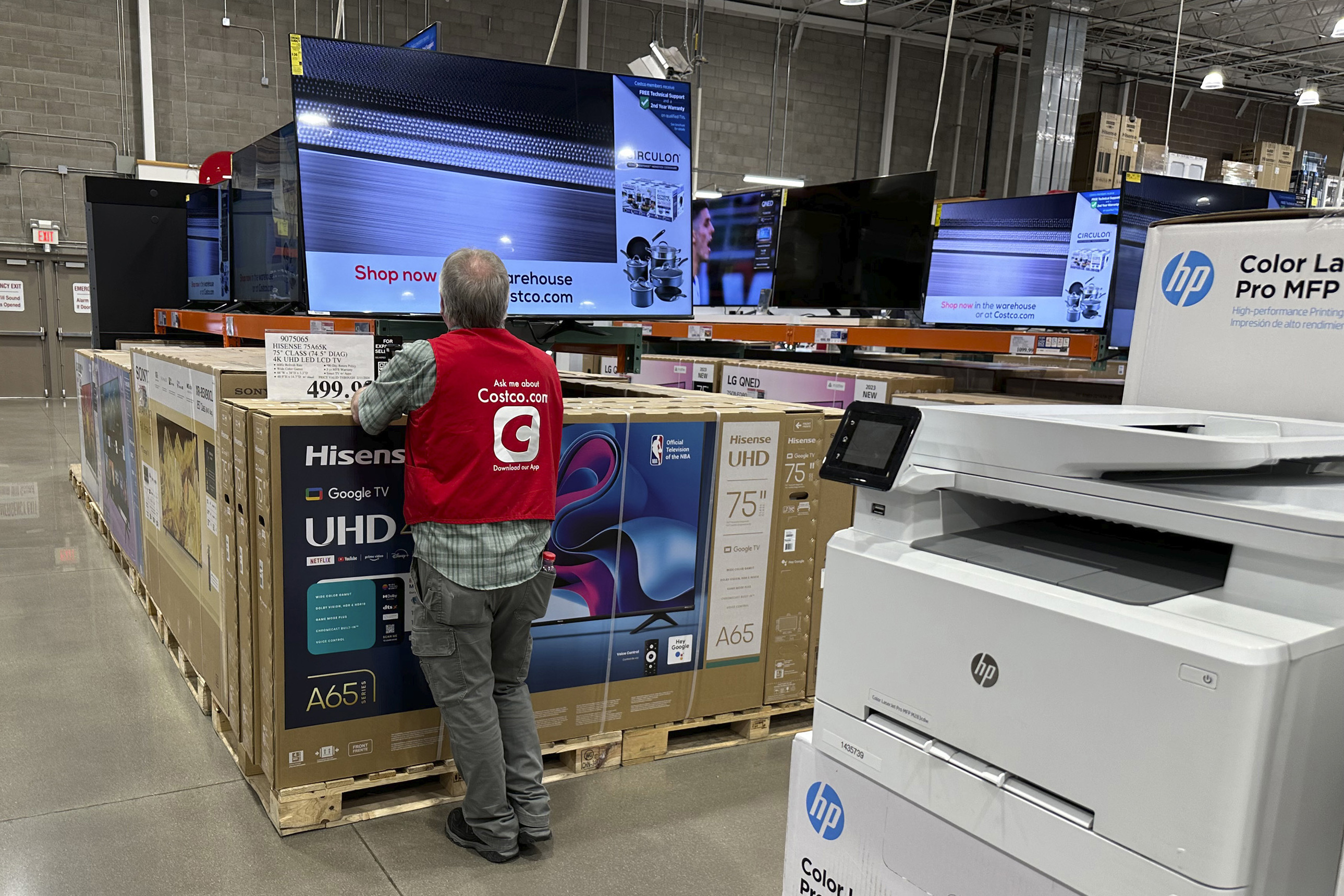 An associate checks over a big-screen television on display in a Costco warehouse Feb. 6, in Colorado Springs, Colo. Annual inflation in the United States cooled last month yet remained elevated, the government reported Tuesday.