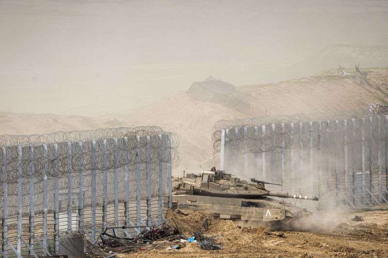 Israeli soldiers drive a tank as they cross the border from inside Gaza Strip in to southern Israel, Tuesday.
