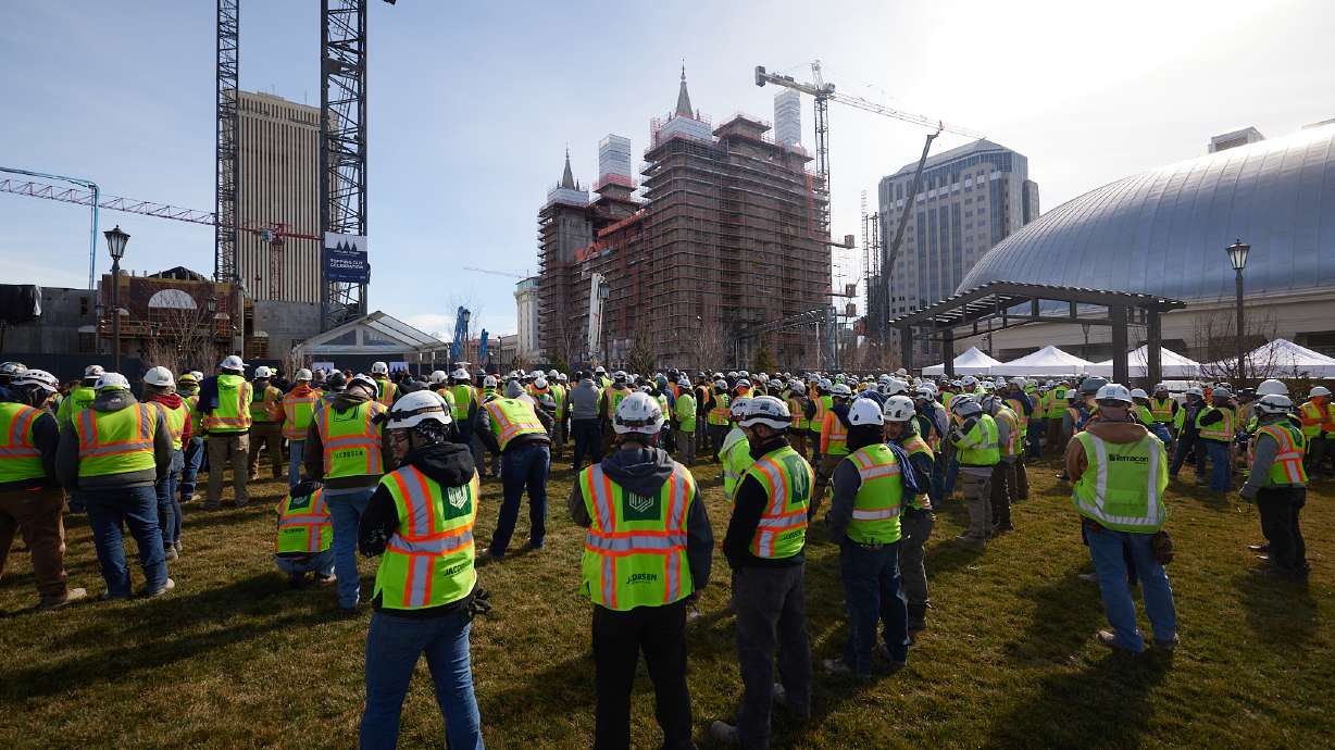 Construction workers celebrate Tuesday as the reinforced frame for the final spire is placed on the Salt Lake Temple on Tuesday.