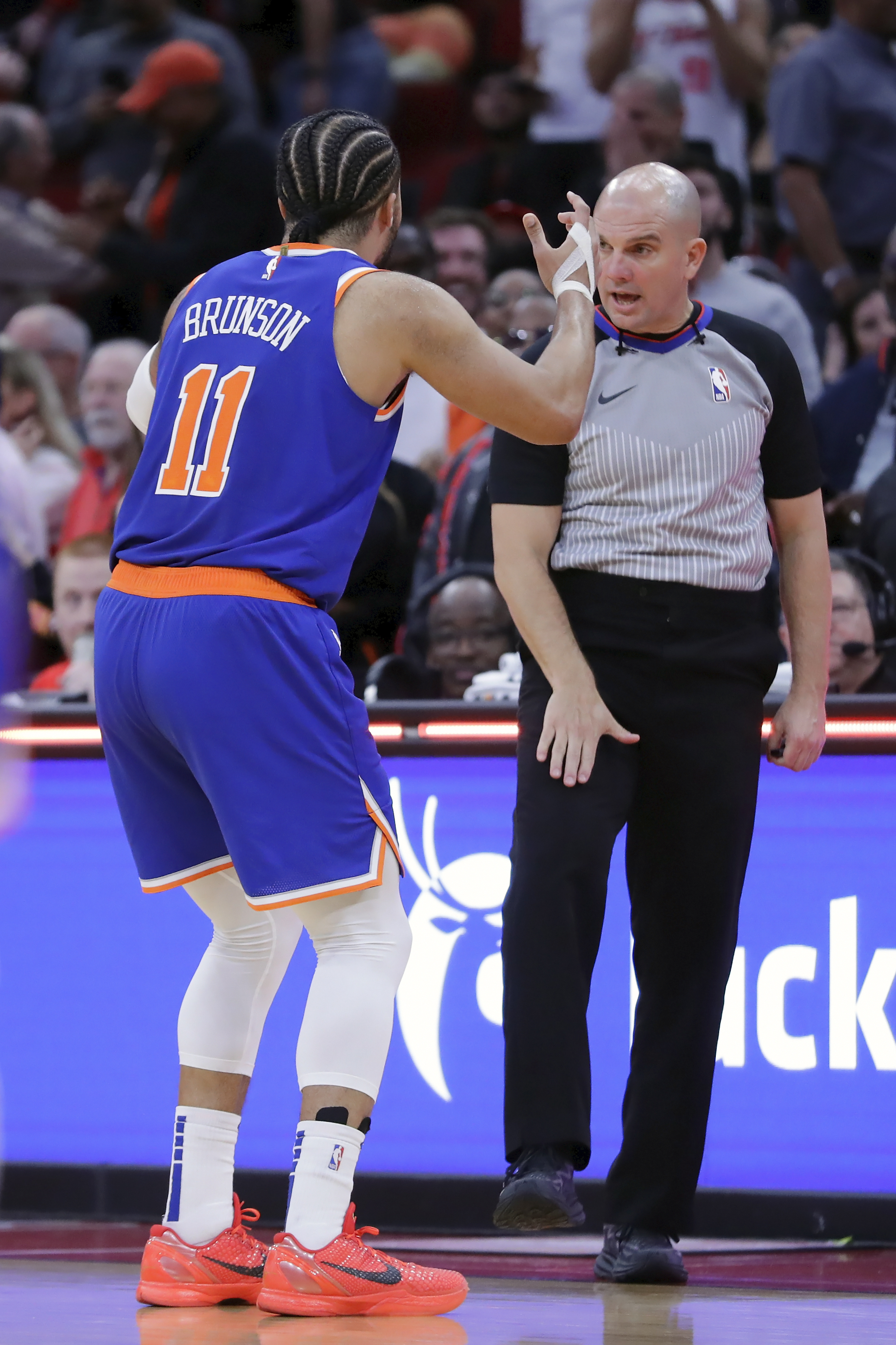 With the game tied and under one second left on the clock, New York Knicks guard Jalen Brunson (11) reacts as he is called for a foul by referee Jacyn Goble, right, when Houston Rockets guard Aaron Holiday was attempting a 3-point shot, setting up the winning free throws for Houston, during the second half of an NBA basketball game Monday, Feb. 12, 2024, in Houston. 