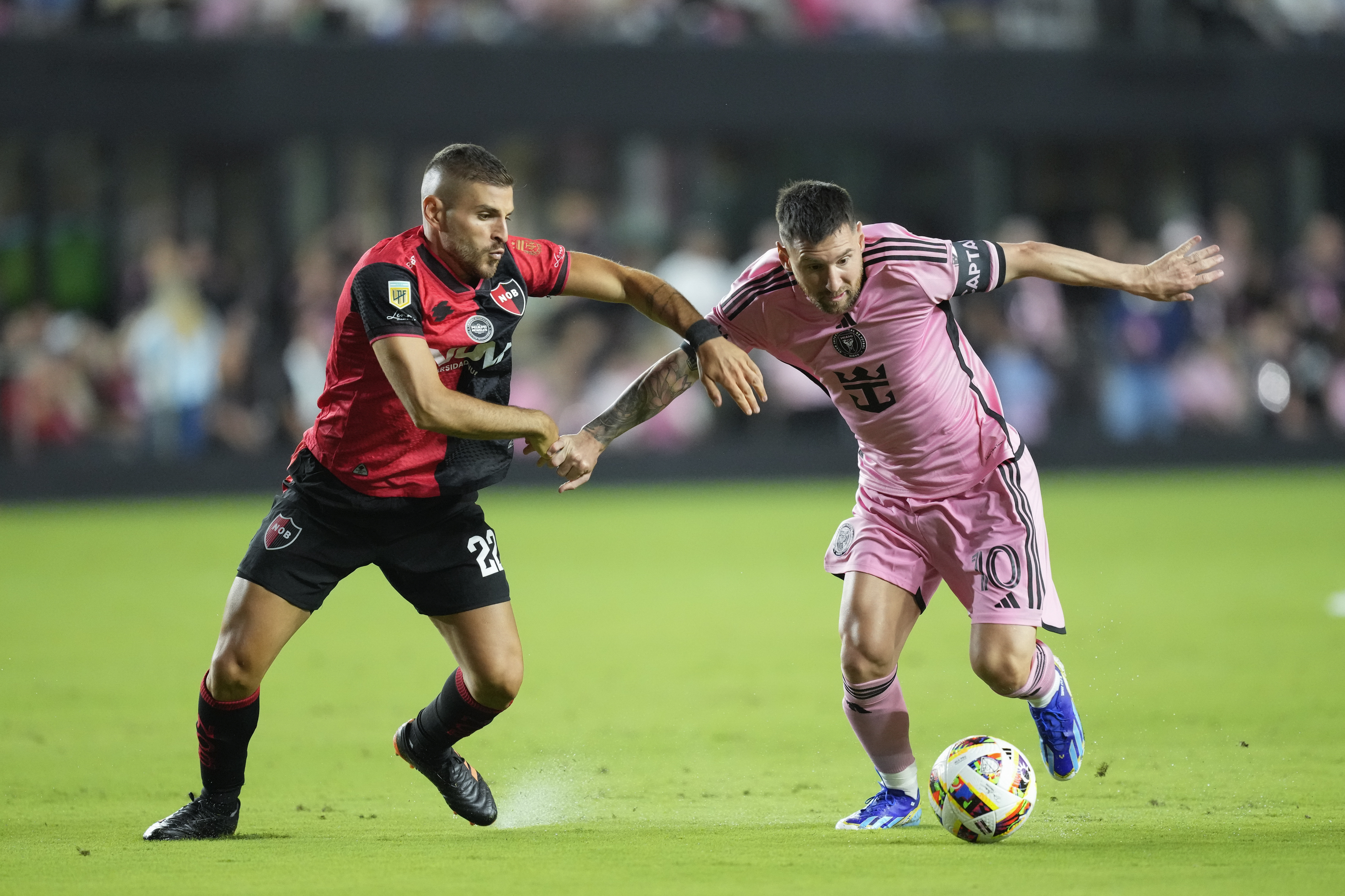 Inter Miami forward Lionel Messi (10) comes under pressure from Newell's Old Boys midfielder Julian Fernandez, left, during the first half of a friendly soccer match, Thursday, Feb. 15, 2024, in Fort Lauderdale, Fla.