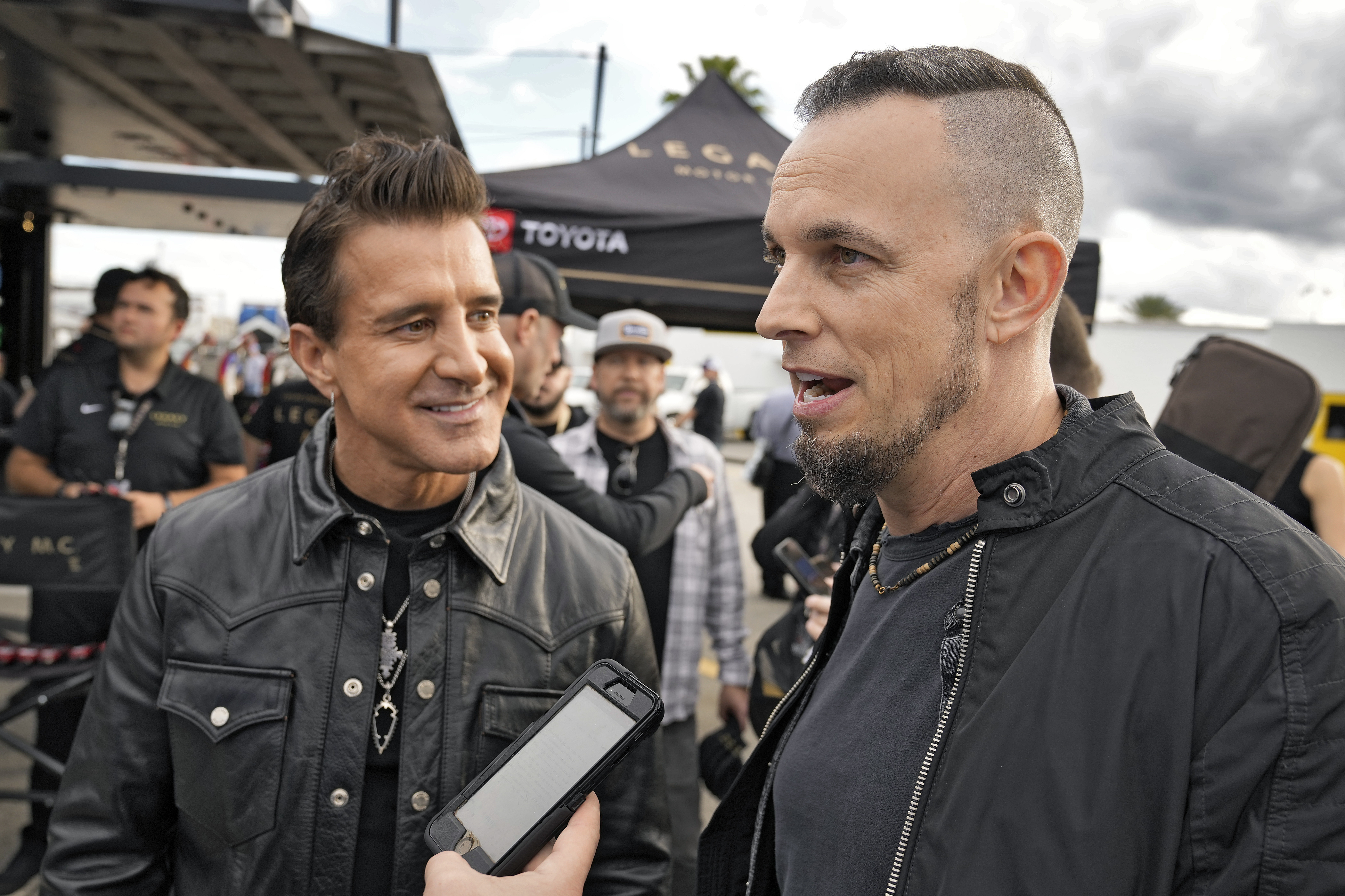 Scott Stapp, left, and Mark Tremonti, right, members of the rock band Creed, take part in an interview during an NASCAR Daytona 500 practice auto race Thursday, Feb. 15, 2024, at Daytona International Speedway in Daytona Beach, Fla. 