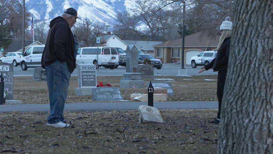 John Cook looks at a broken headstone with Susan Orifici, while other broken headstones can be seen in the background at the Grantsville City Cemetery in Grantsville on Thursday.