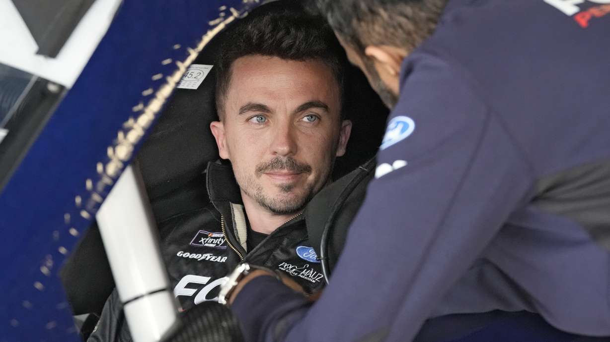 Race car driver and actor Frankie Muniz, left, talks to a crew member before a practice run Friday at Daytona International Speedway in Daytona Beach, Fla.