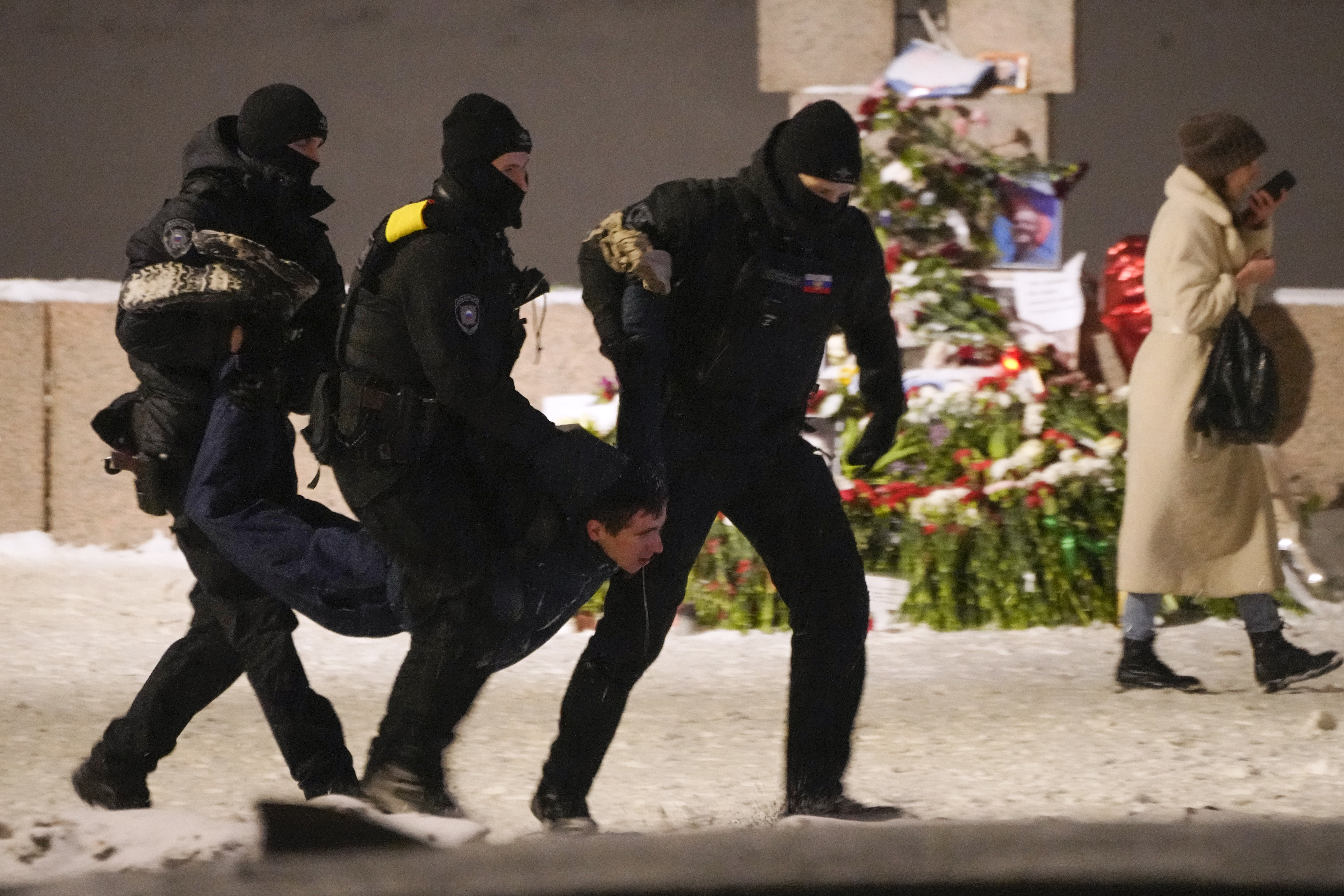 Police officers detain a man laying flowers to Alexei Navalny at the Memorial to Victims of Political Repression in St. Petersburg, Russia on Friday.