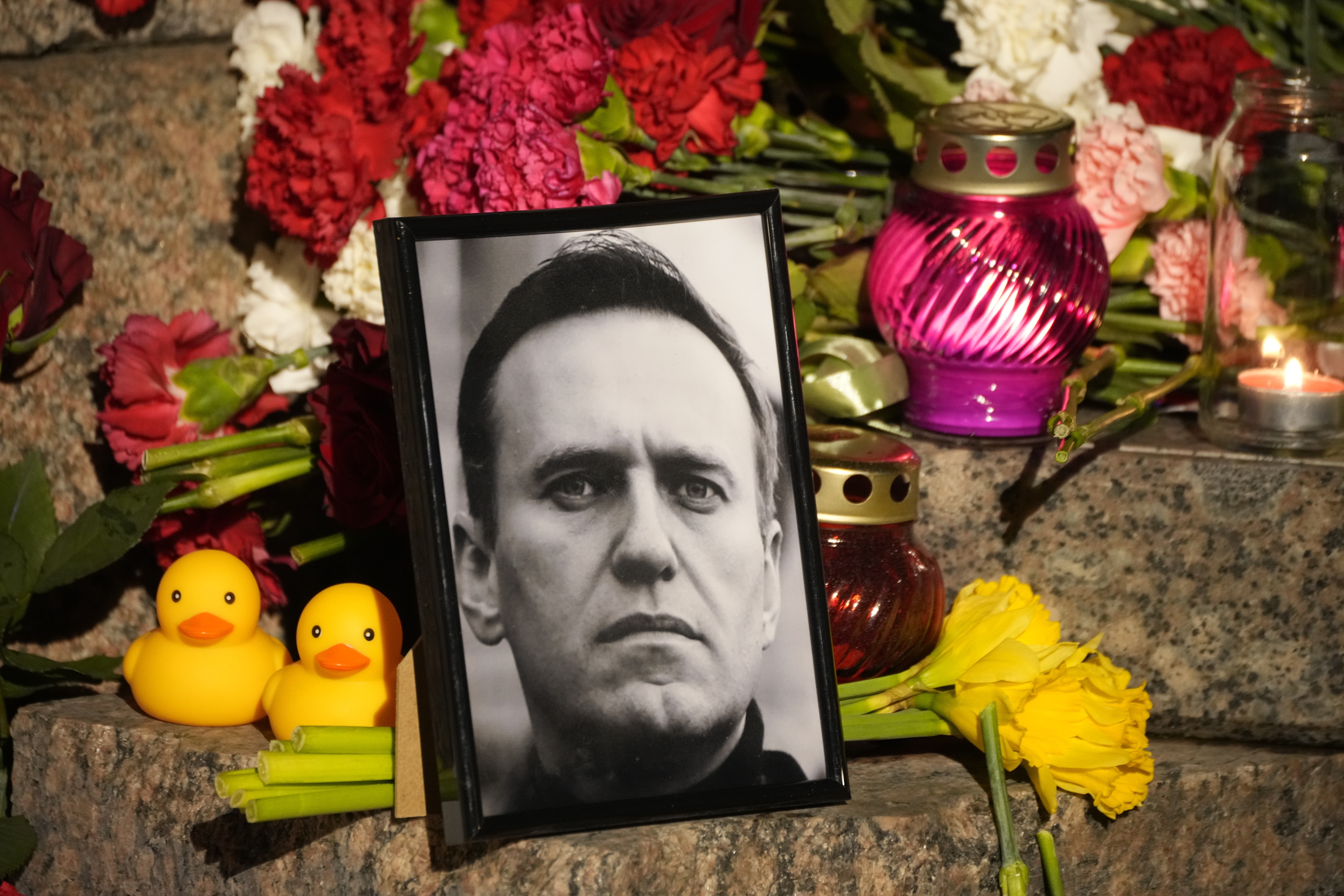 A portrait of Russian opposition leader Alexei Navalny, flowers and candles are laid on a ground as people gather to pay their last respect to Alexei Navalny at the Memorial to Victims of Political Repression in St. Petersburg, Russia on Friday