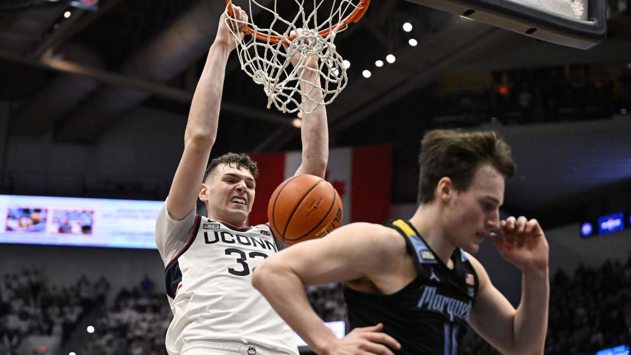UConn center Donovan Clingan dunks behind Marquette guard Tyler Kolek (11) in the first half of an NCAA college basketball game, Saturday, Feb. 17, 2024, in Hartford, Conn.