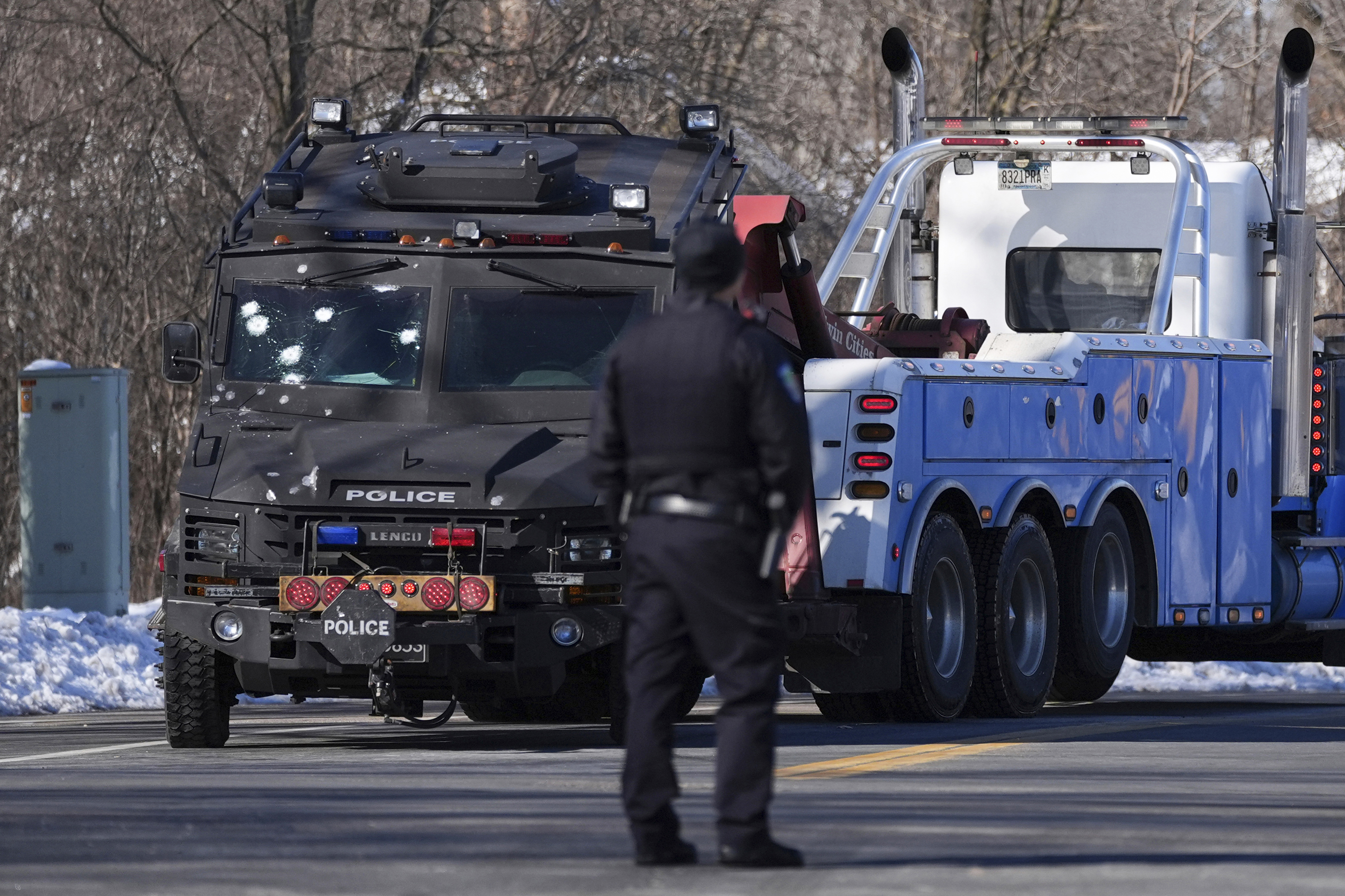 A police vehicle with what appears to be bullet pockmarks is towed near the scene where two police officers and a first responder were shot and killed Sunday in Burnsville, Minn.