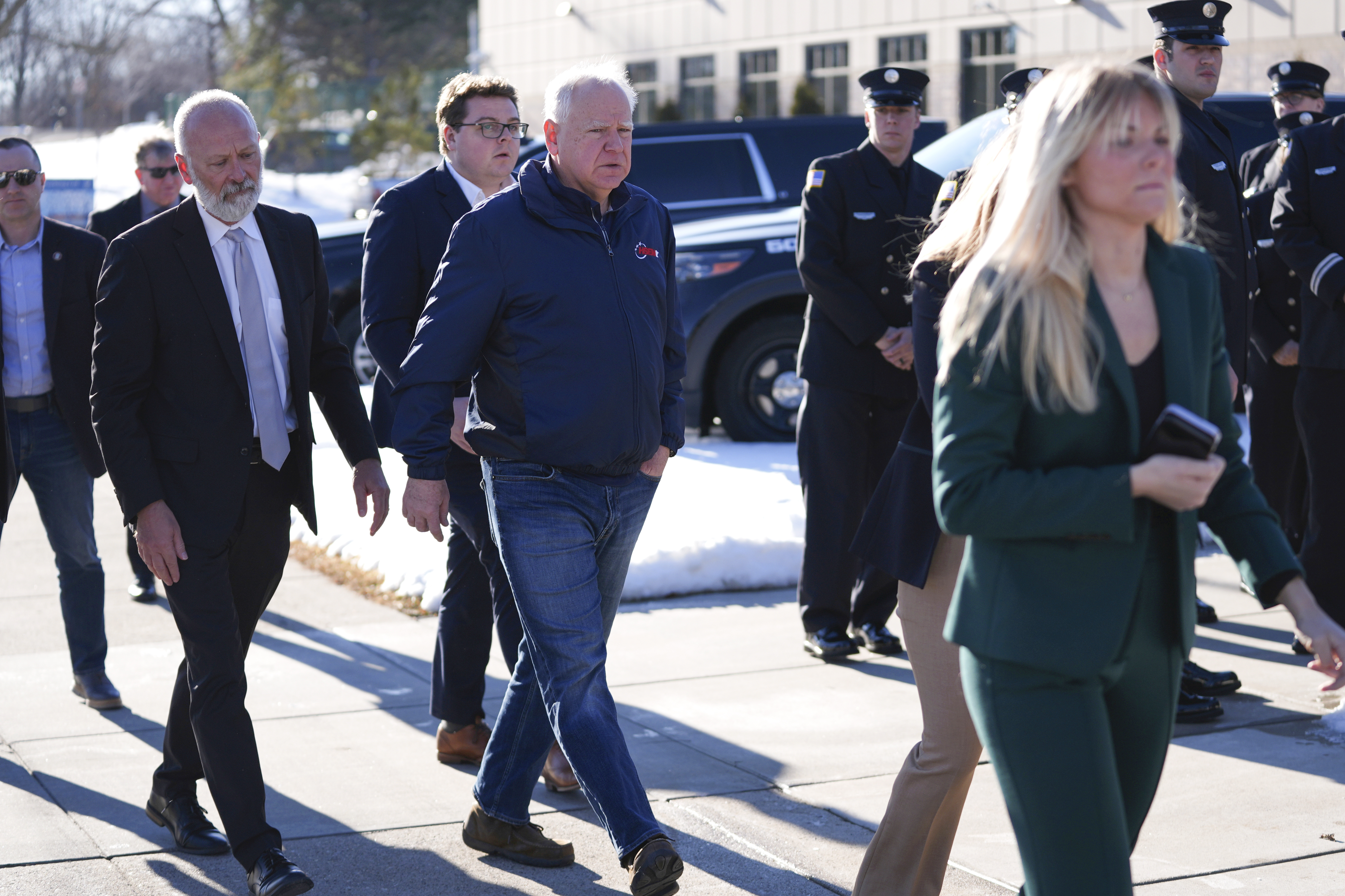 Minnesota Gov. Tim Walz, center, arrives at City Hall before a press conference after two police officers and a first responder were shot and killed Sunday in Burnsville, Minn.