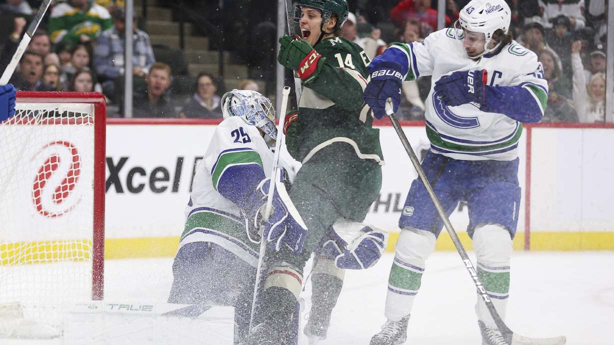 Minnesota Wild center Joel Eriksson Ek (14) celebrates after scoring a goal passed Vancouver Canucks goaltender Casey DeSmith (29) while defenseman Quinn Hughes (43) watches during the first period of an NHL hockey game Monday, Feb. 19, 2024, in St. Paul, Minn.