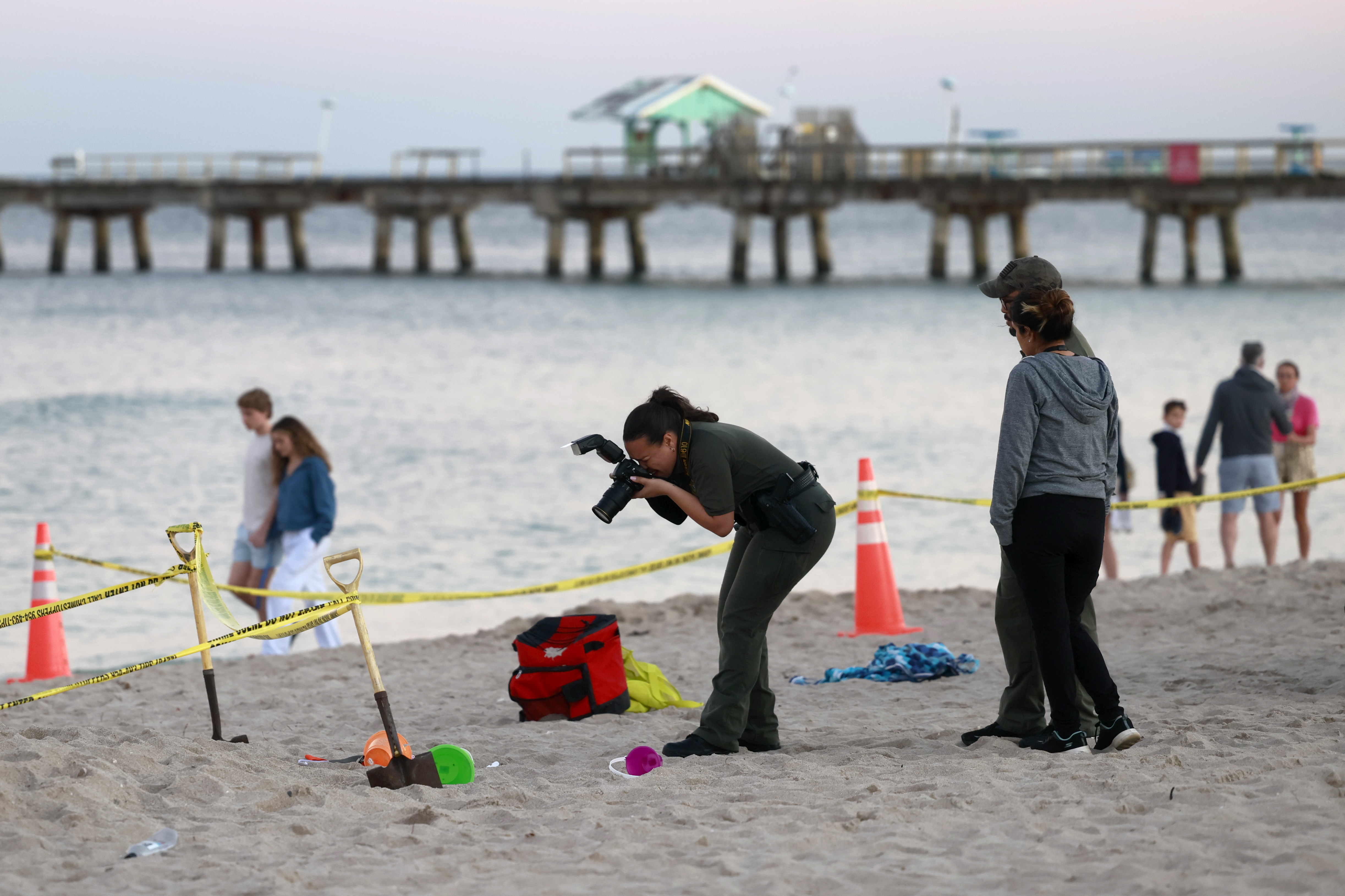 Investigators on the beach in Lauderdale-by-the-Sea, Fla., take photos of the scene of a sand collapse on Tuesday. A young girl was buried in sand and died Tuesday.