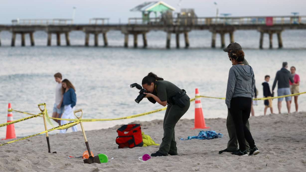 Investigators on the beach in Lauderdale-by-the-Sea, Fla., take photos of the scene of a sand collapse on Tuesday. A young girl was buried in sand and died Tuesday.