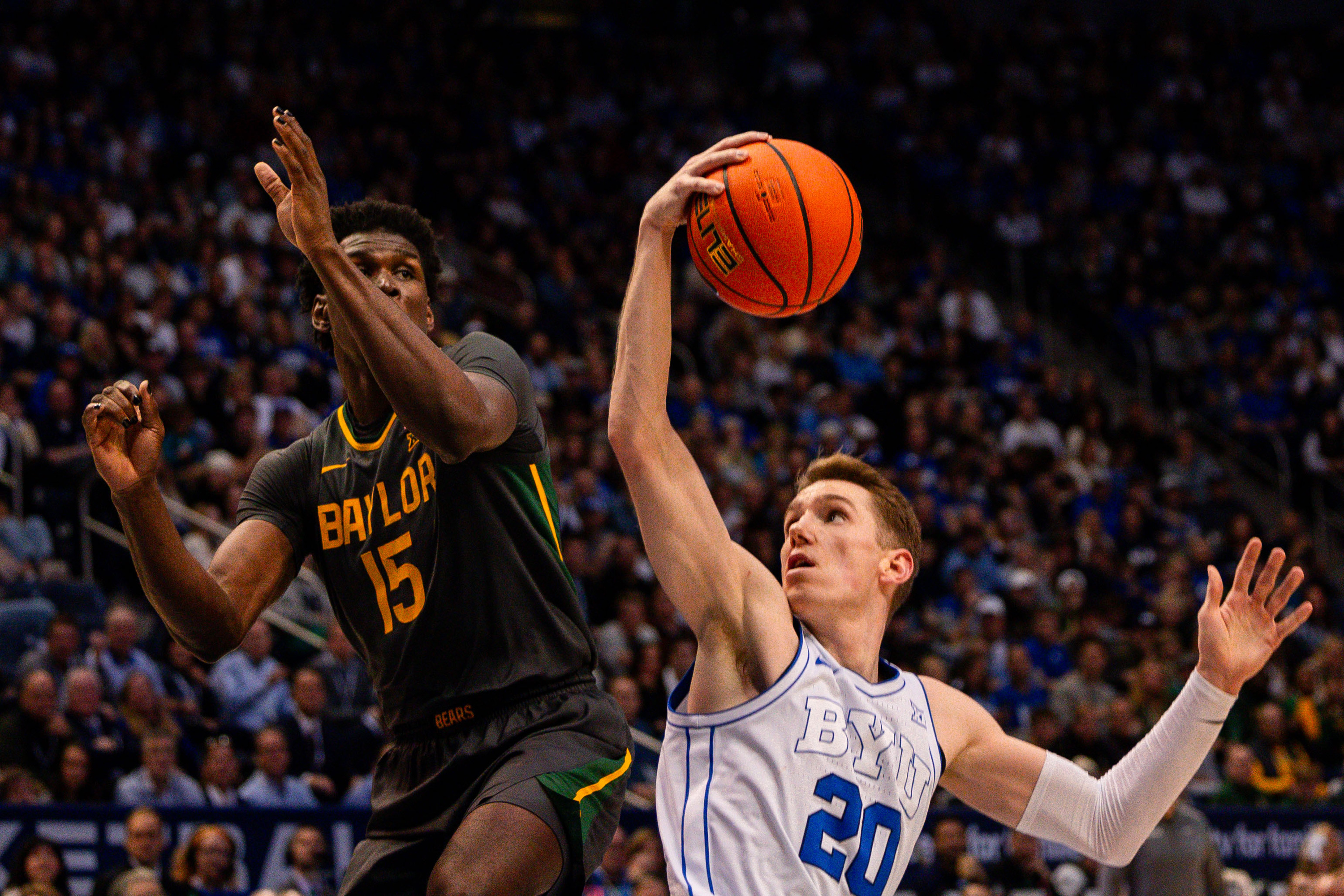 Brigham Young guard Spencer Johnson (20) fakes to shoot the ball with Baylor forward Josh Ojianwuna (15) jumping up to block the shot during a men’s college basketball game between Brigham Young University and Baylor University at the Marriott Center in Provo on Tuesday, Feb. 20, 2024.