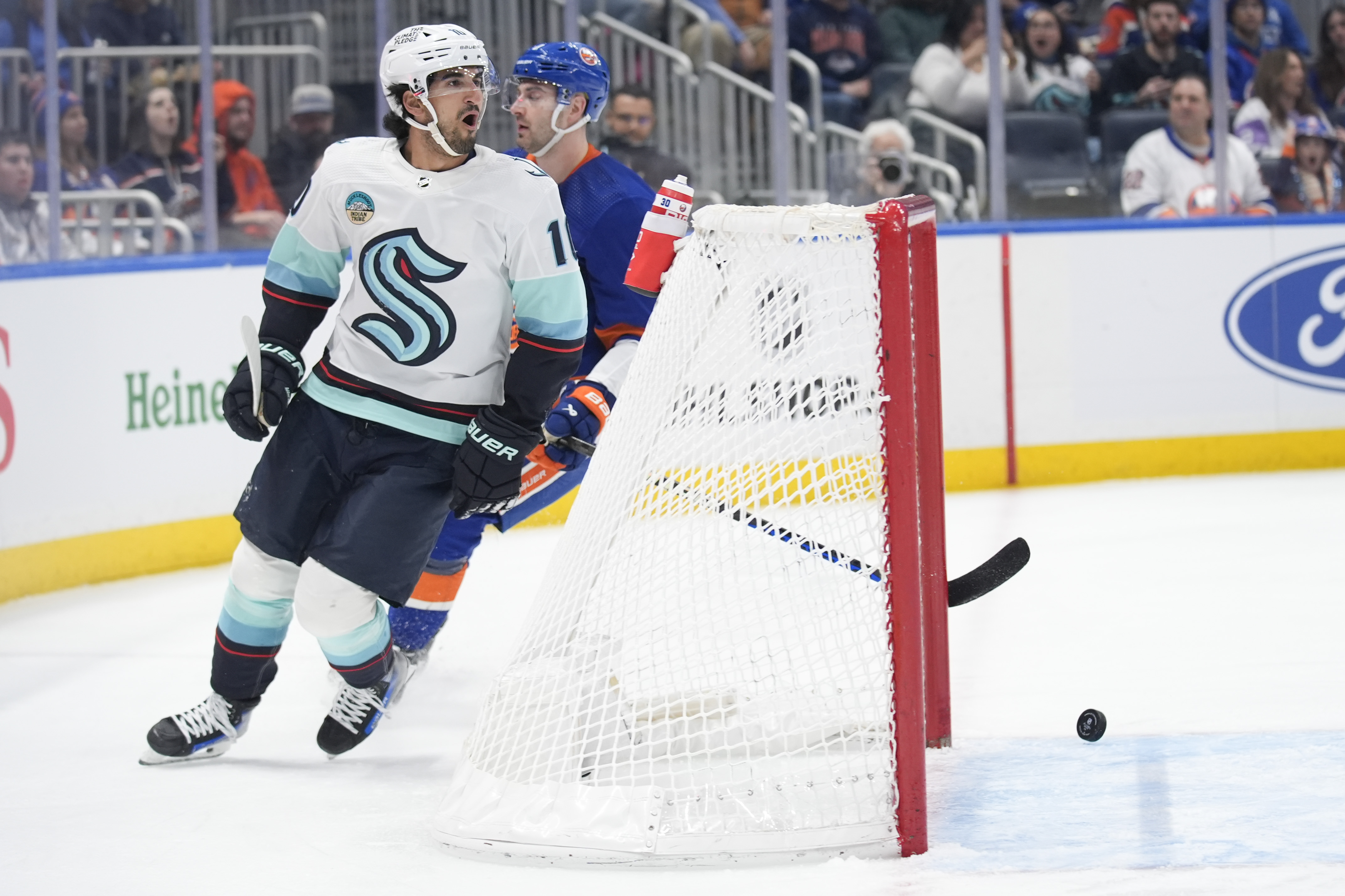 Seattle Kraken's Matty Beniers (10), left, reacts after scoring during the first period of an NHL hockey game against the New York Islanders, Tuesday, Feb. 13, 2024, in Elmont, N.Y. 