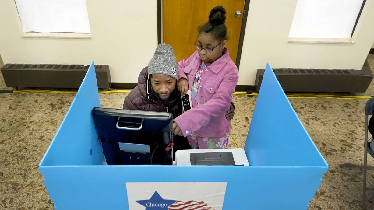 Christopher Sandridge teaches his daughter Christina the voting process as he casts a ballot at the Rev. Dr. Martin Luther King Community Center on the Southside of Chicago, Nov. 8, 2022.
